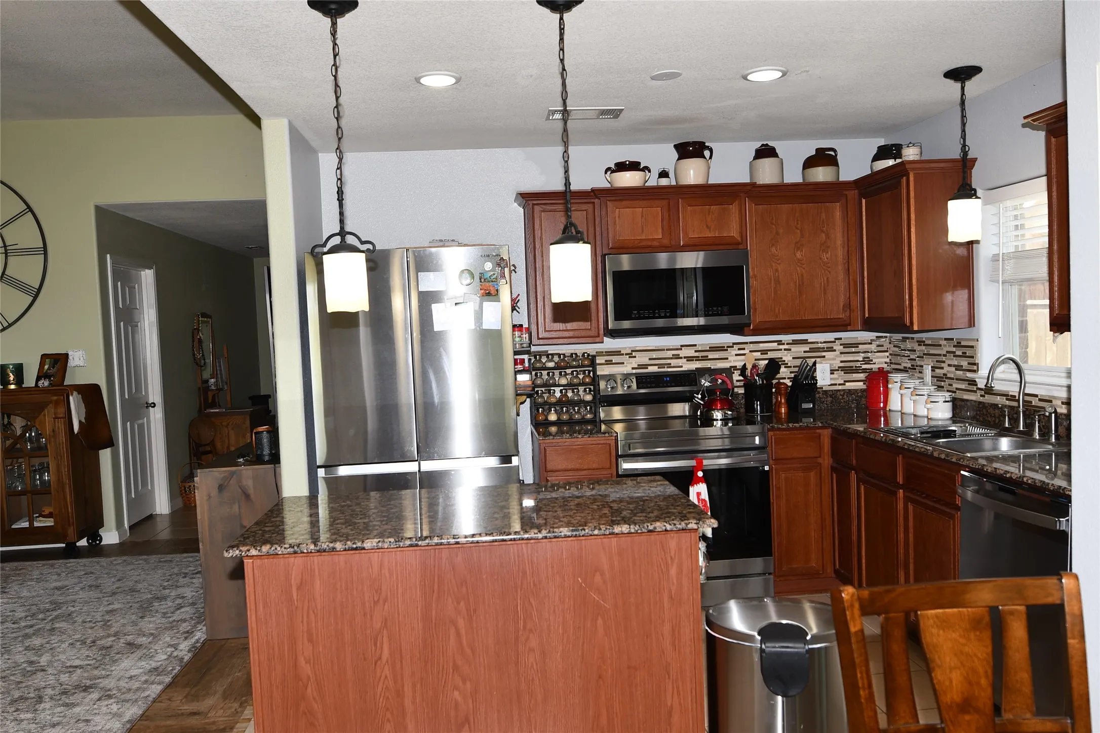 Kitchen featuring wood cabinetry, stainless steel appliances, a tile backsplash, and stone countertops