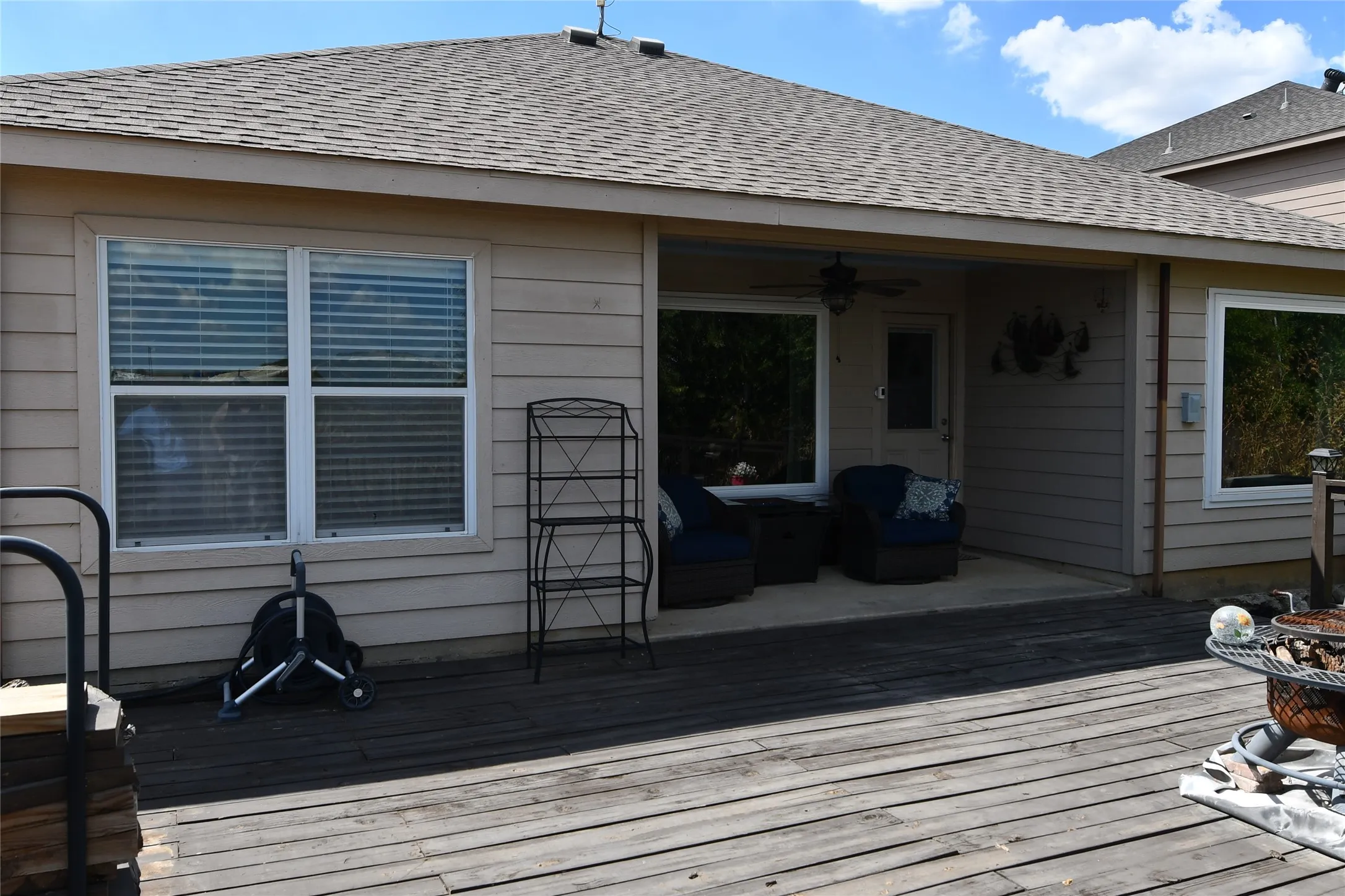 Expansive wood deck with a covered patio area and multiple windows