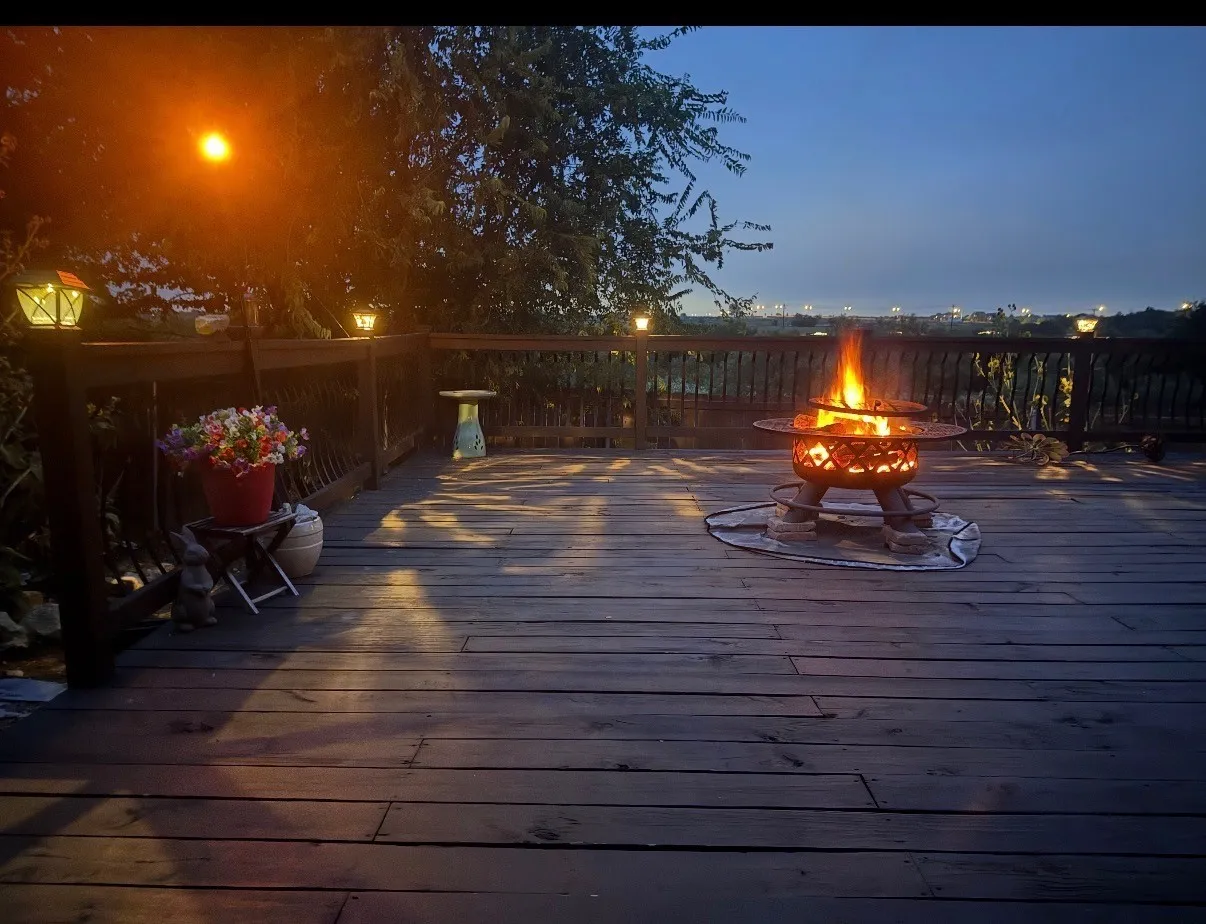 Expansive wooden deck with a built-in fire pit and perimeter railing