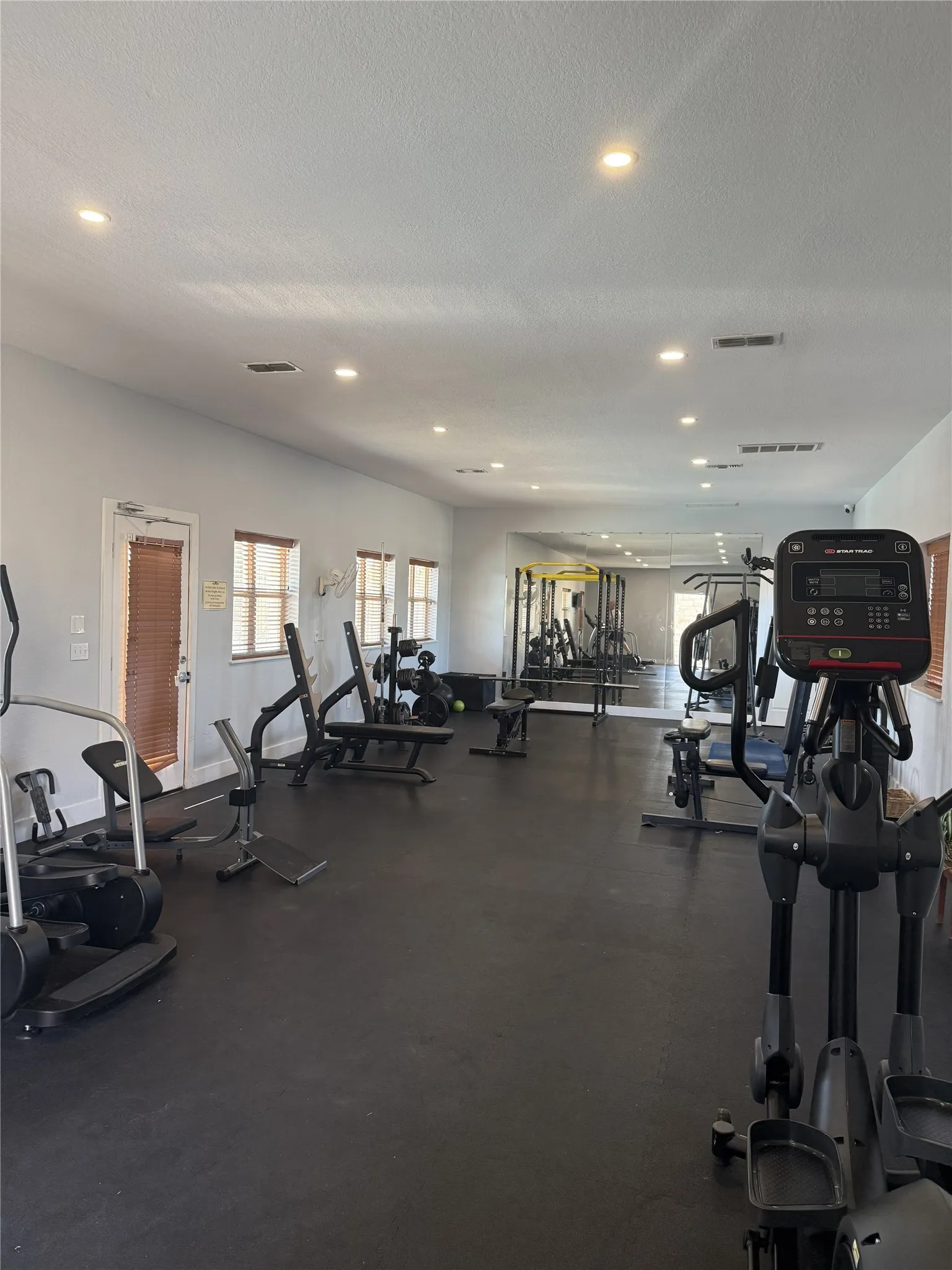 Fitness center with recessed lighting, multiple windows, and dark rubberized flooring