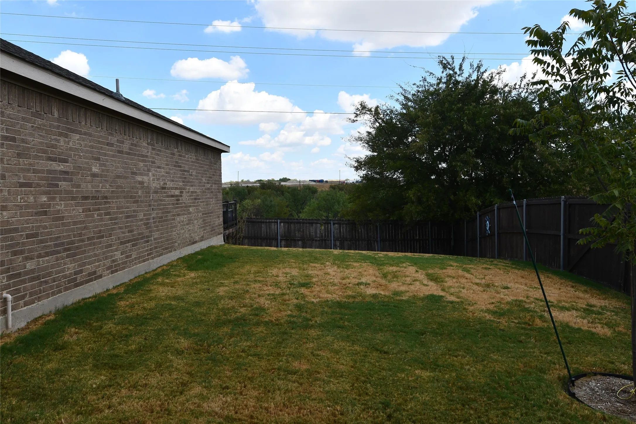 Brick exterior with a dark-stained wood privacy fence and mature trees