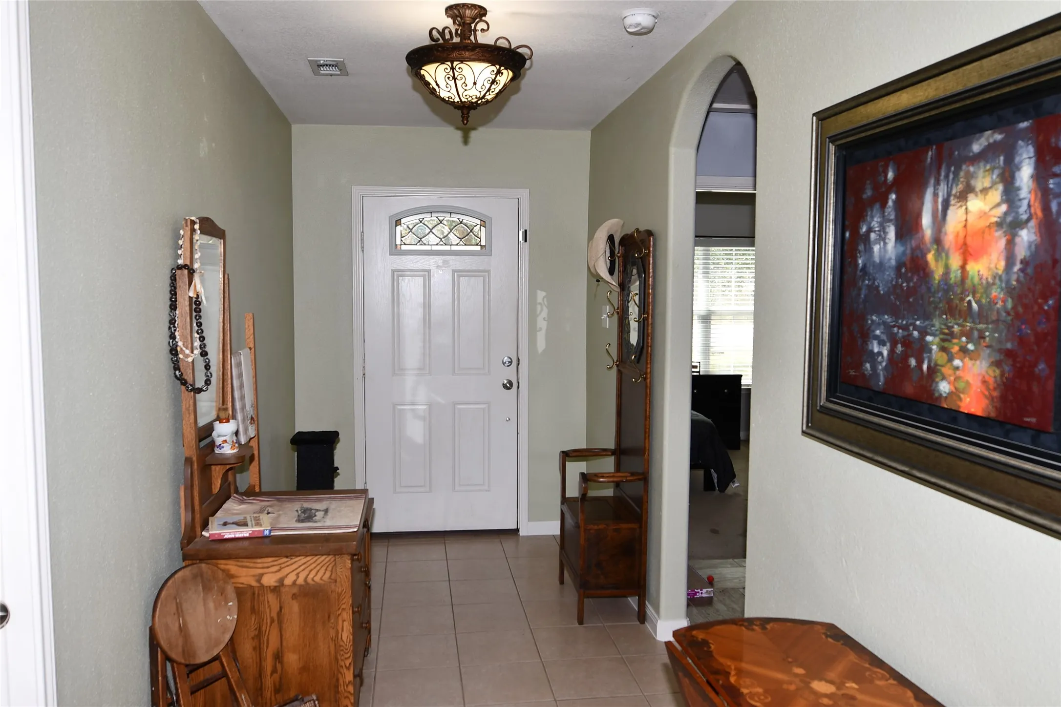 Wide entry at front  door with decorative  tile flooring, and arched doorway