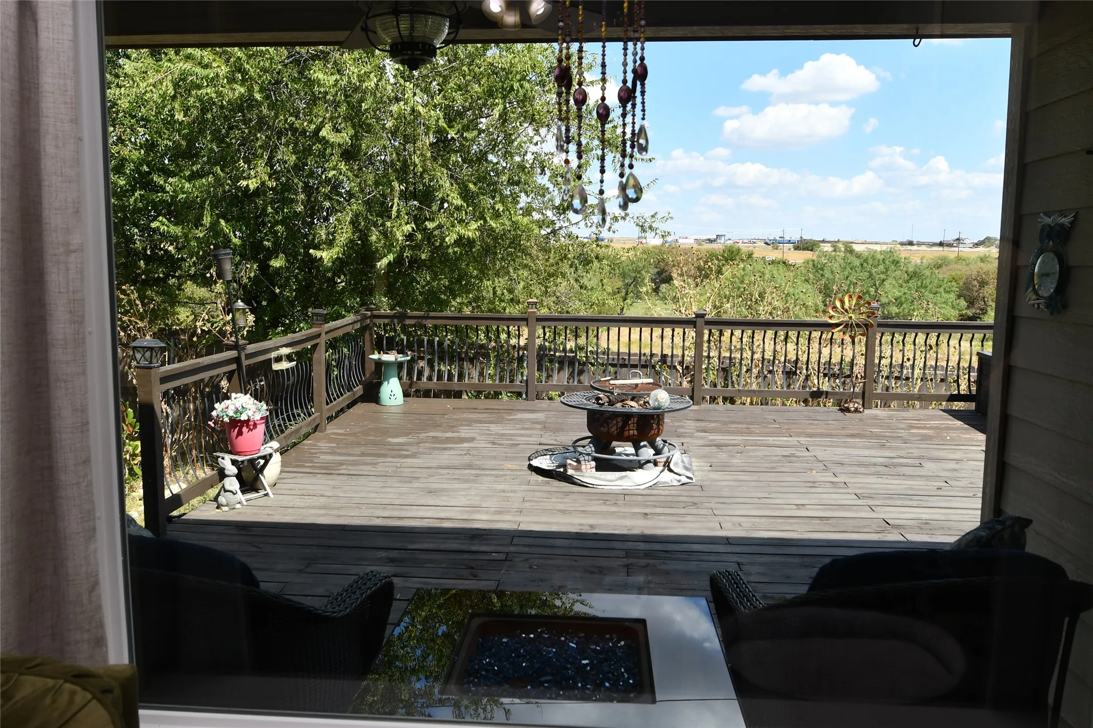 Expansive composite deck featuring wood-finish decking, sturdy railing with vertical balusters, and mature tree canopy bordering the property