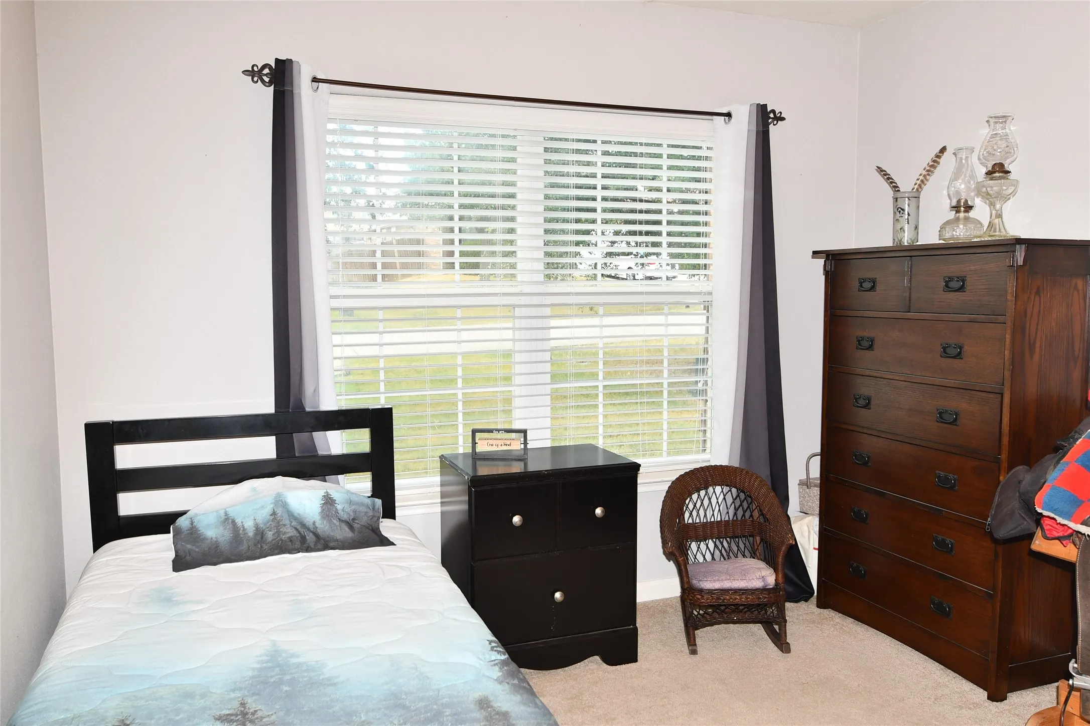 Bright interior space with a large window featuring horizontal blinds and dark curtain panels