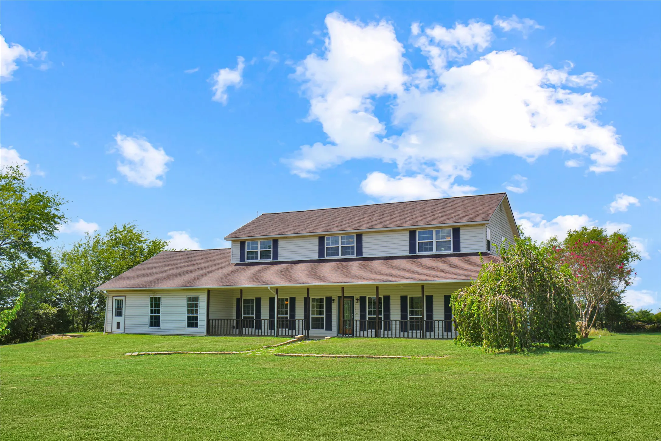 Two-story residence with a brown shingle roof, white siding, and a full-width covered porch