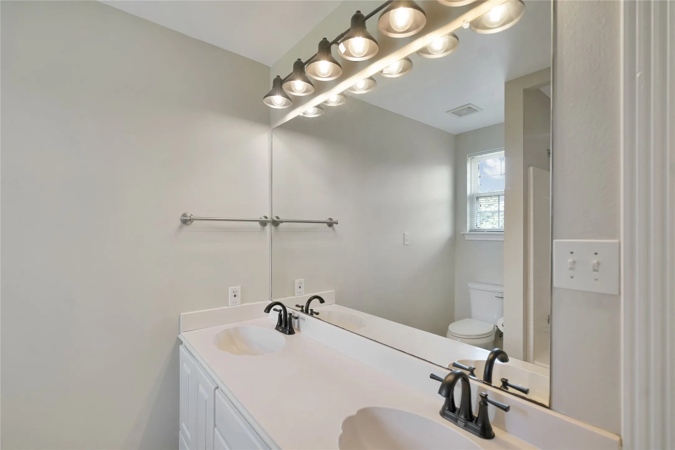 Dual vanity with integrated sinks, white cabinetry, and oil-rubbed bronze fixtures