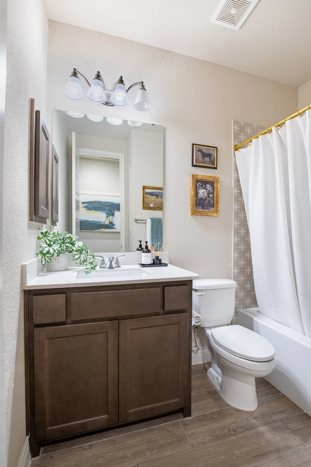 Built-in vanity with a white countertop and undermount sink, wood-finish flooring, and a tub with a shower fixture