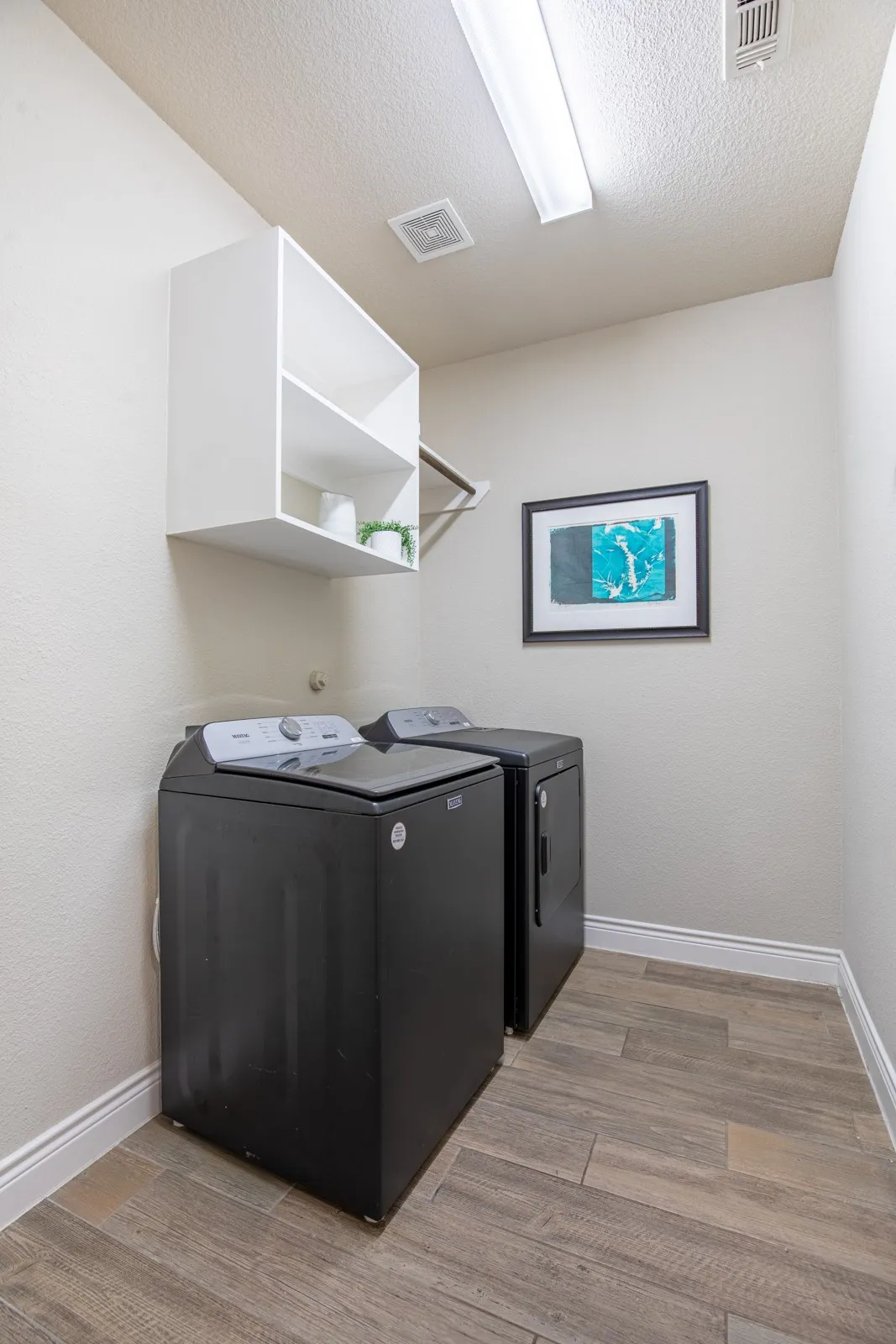 Wood-finish flooring, overhead built-in shelving, and a garment rod
