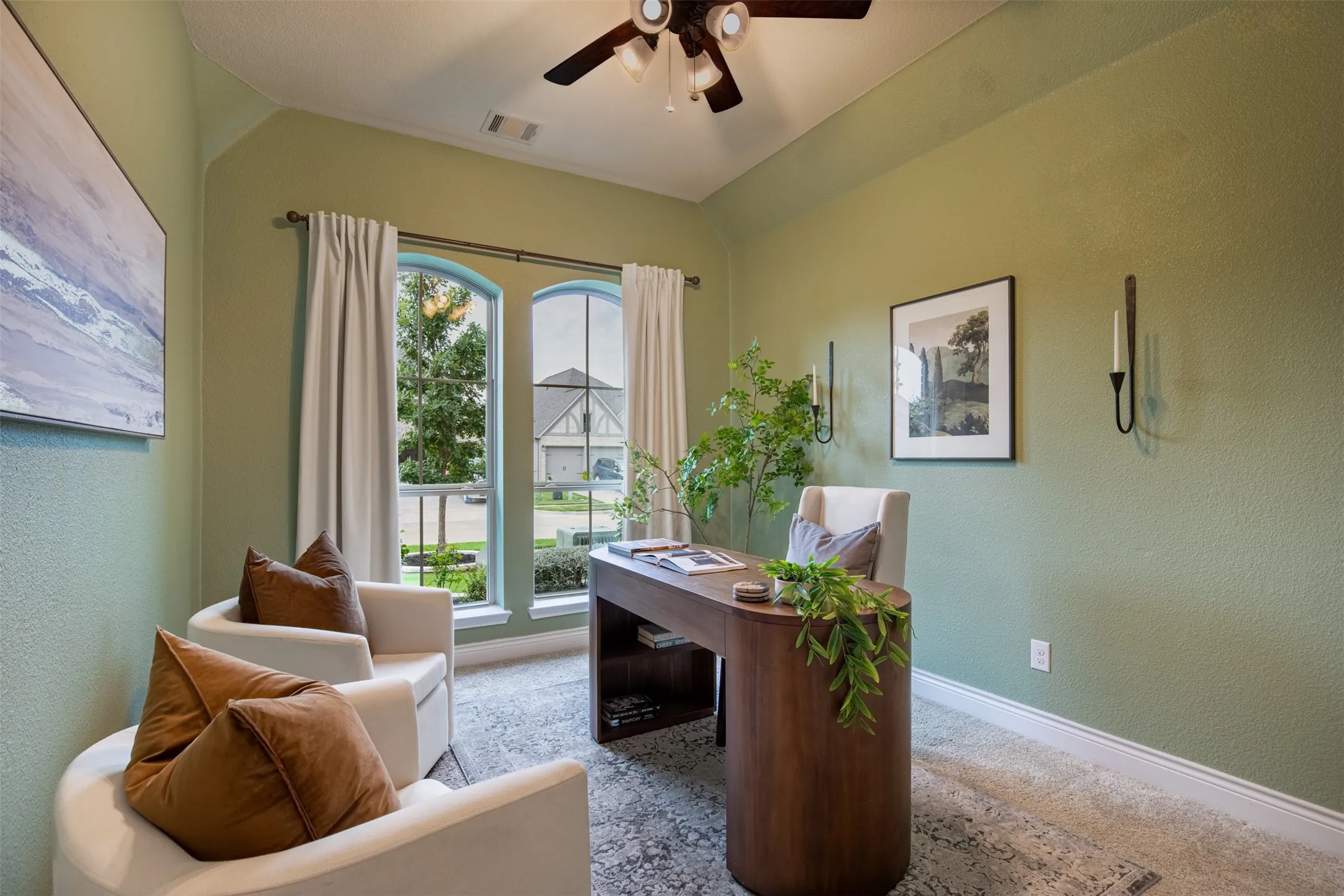Dual arched windows, ceiling fan, and built-in wall sconces