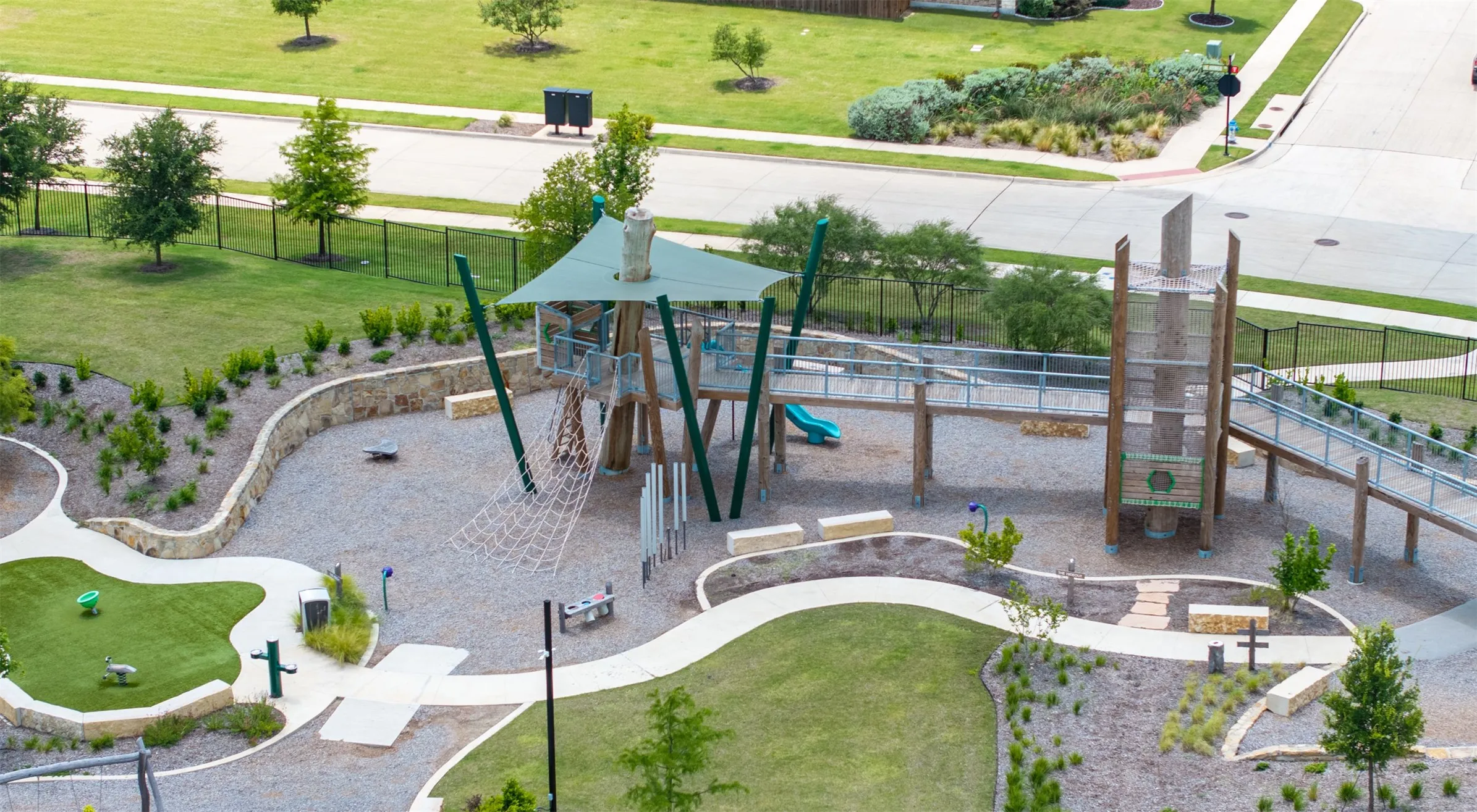 Community amenity area featuring a multi-level play structure, extensive hardscaping, and distinct recreational zones