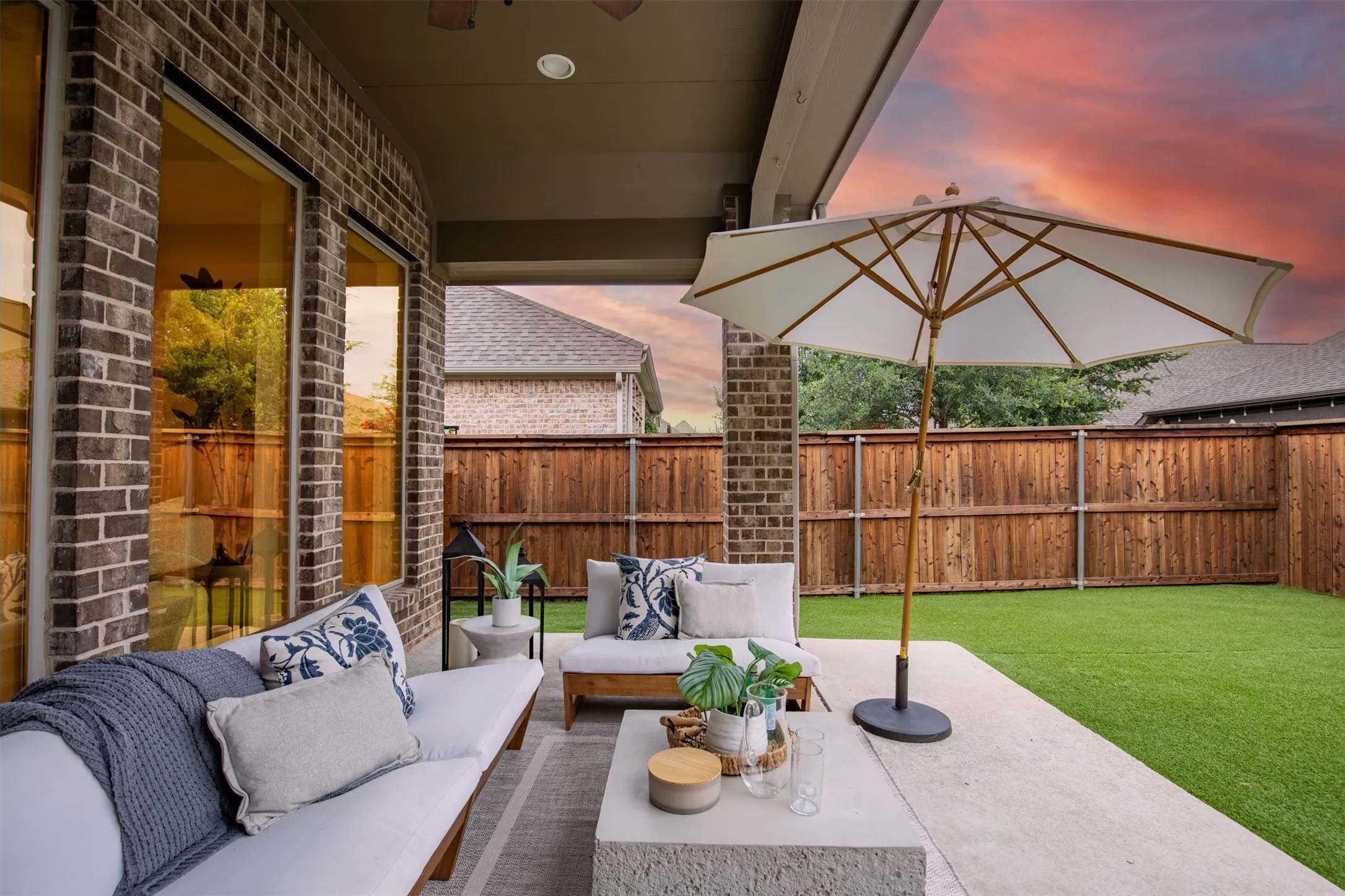 Covered patio featuring a concrete slab, brick exterior, and a privacy fence