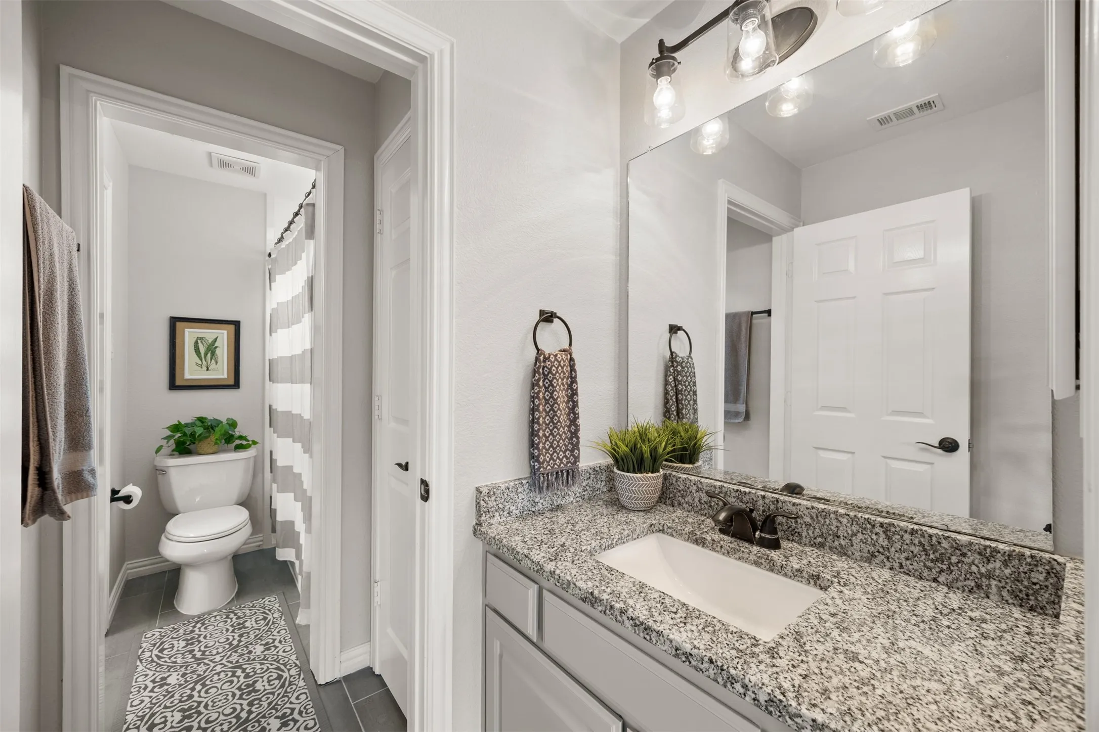 A beautifully remodeled Jack & Jill bath with designer tile connects two bedrooms