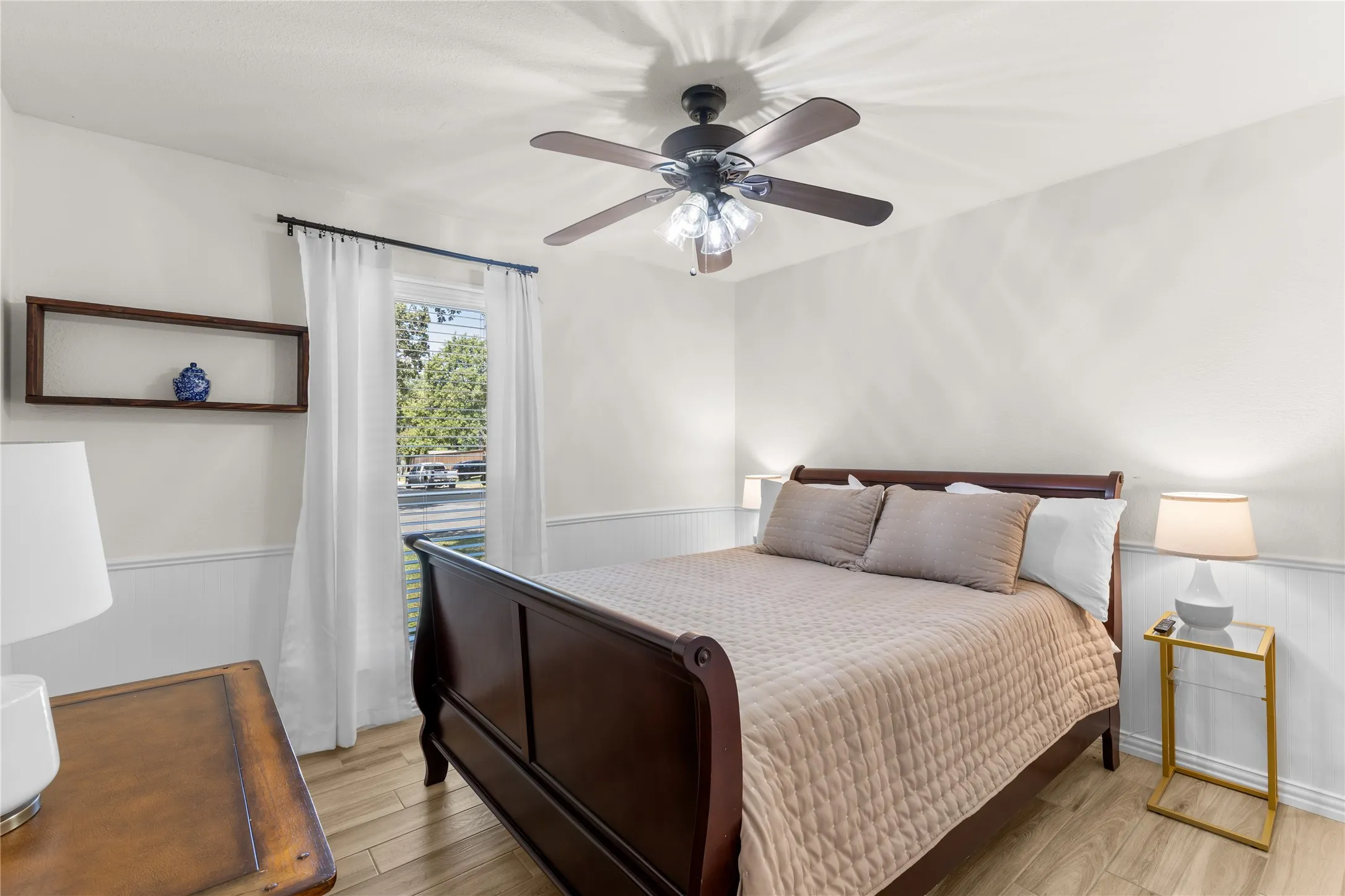 Wood-finish flooring, wainscoting, and a ceiling fan with integrated lighting