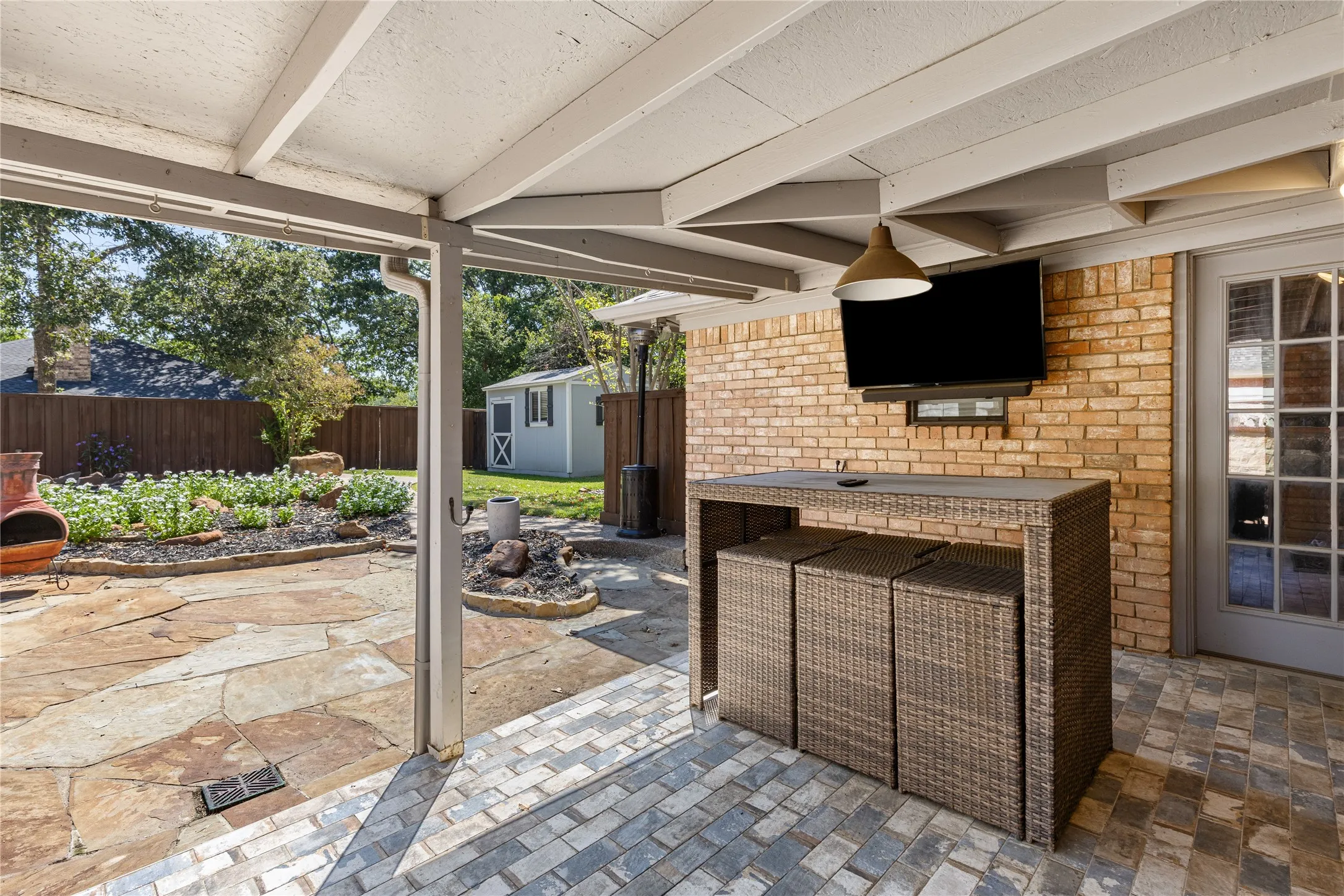Covered patio featuring brick-finish siding, a ceiling-mounted light fixture, and a multi-pane glass door