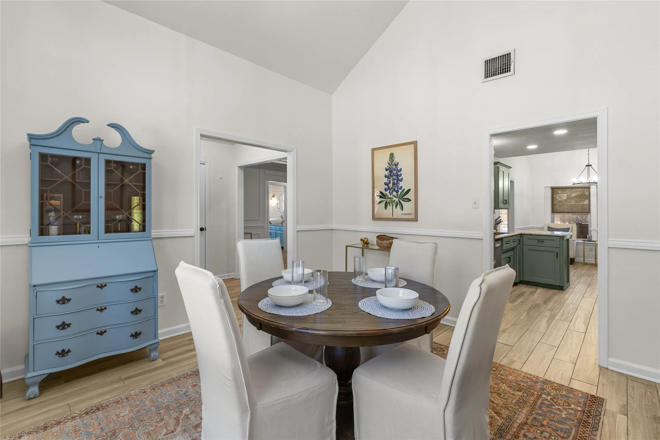 Vaulted ceiling, chair rail molding, wood-finish flooring, recessed lighting, and a pass-through opening