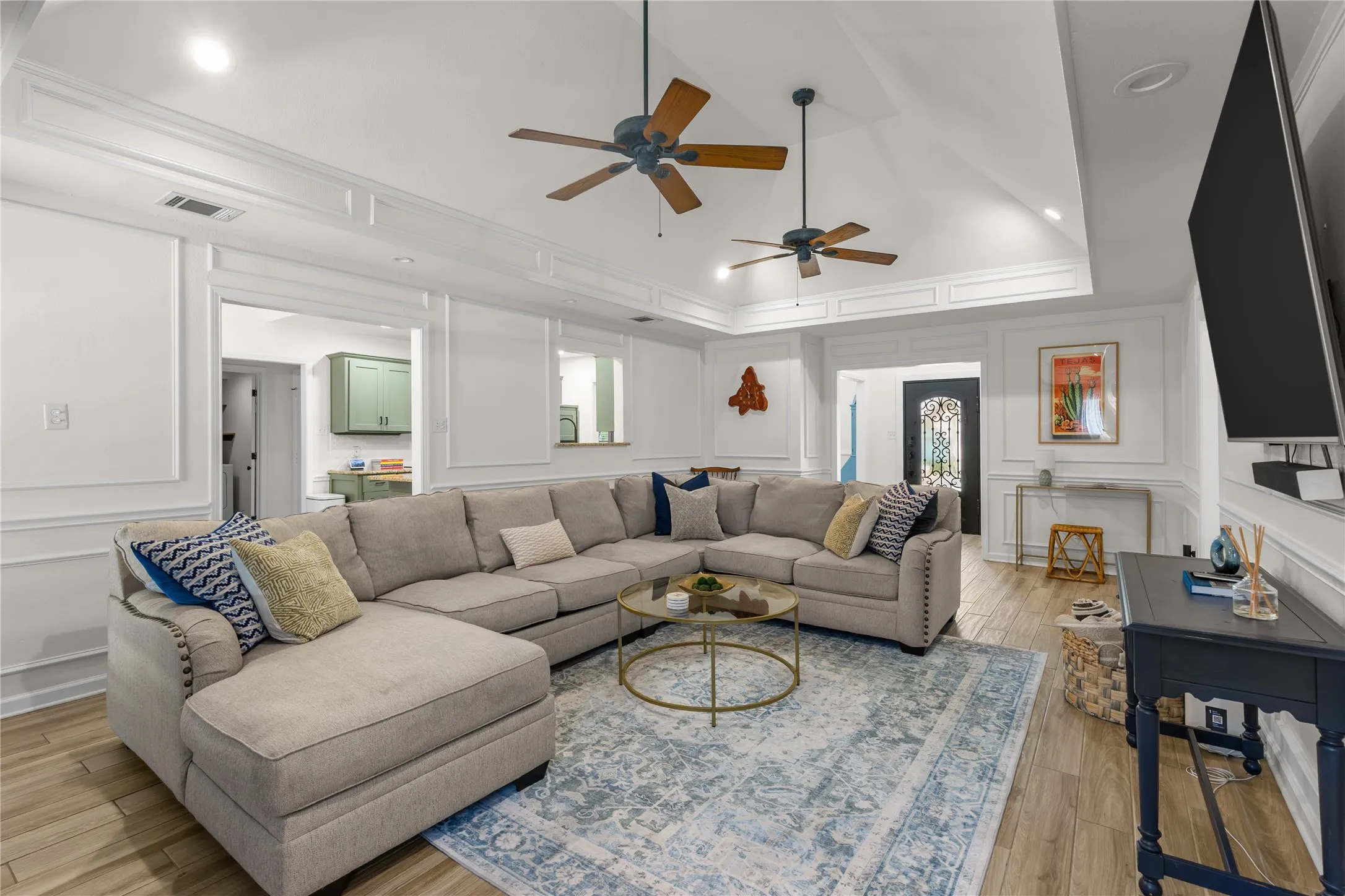 Vaulted ceiling with recessed lighting, wood-finish flooring, accent wall paneling, and an ornate front door
