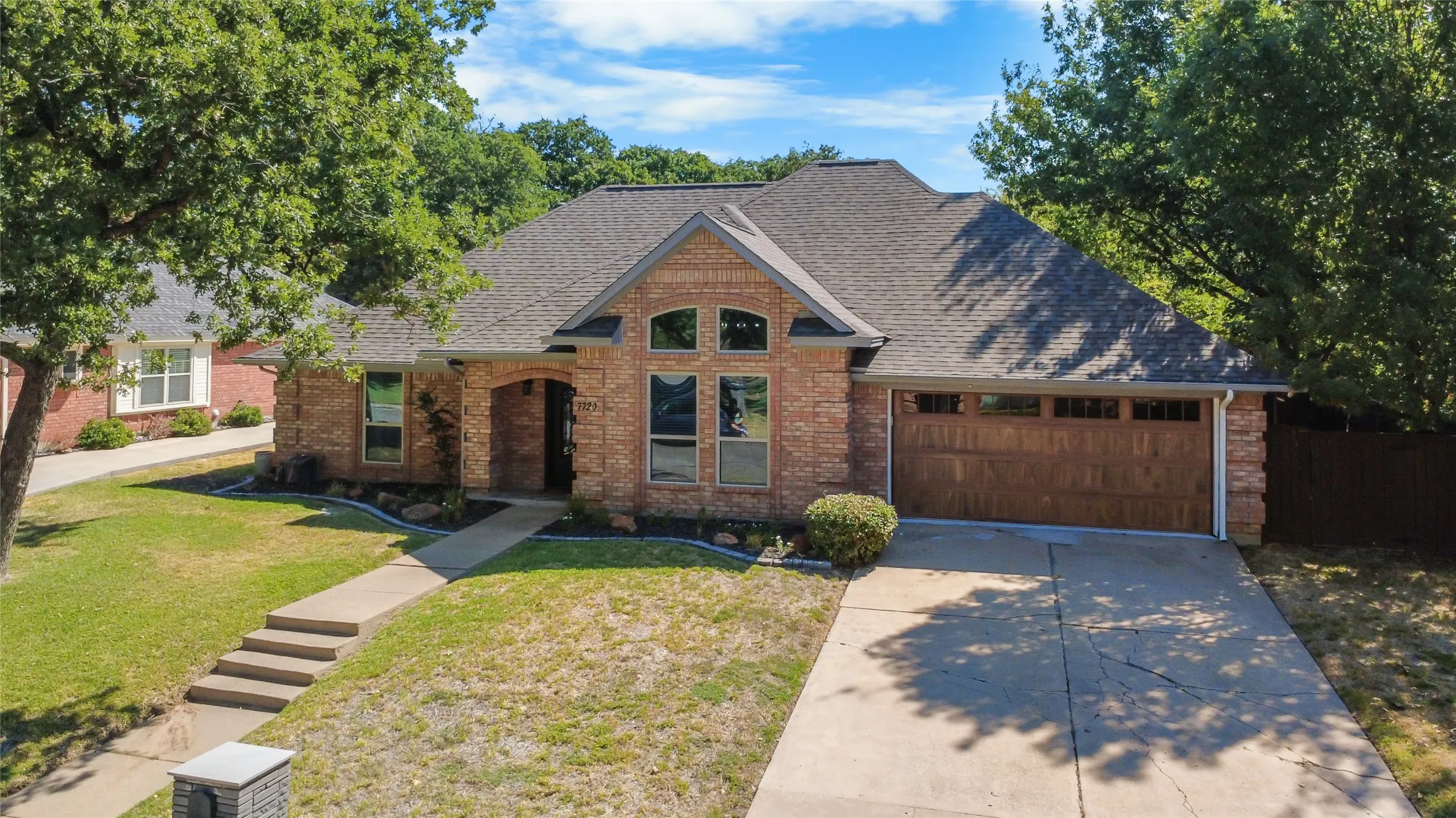 Brick facade with arched entry, multi-pane windows, and a wood-finish garage door