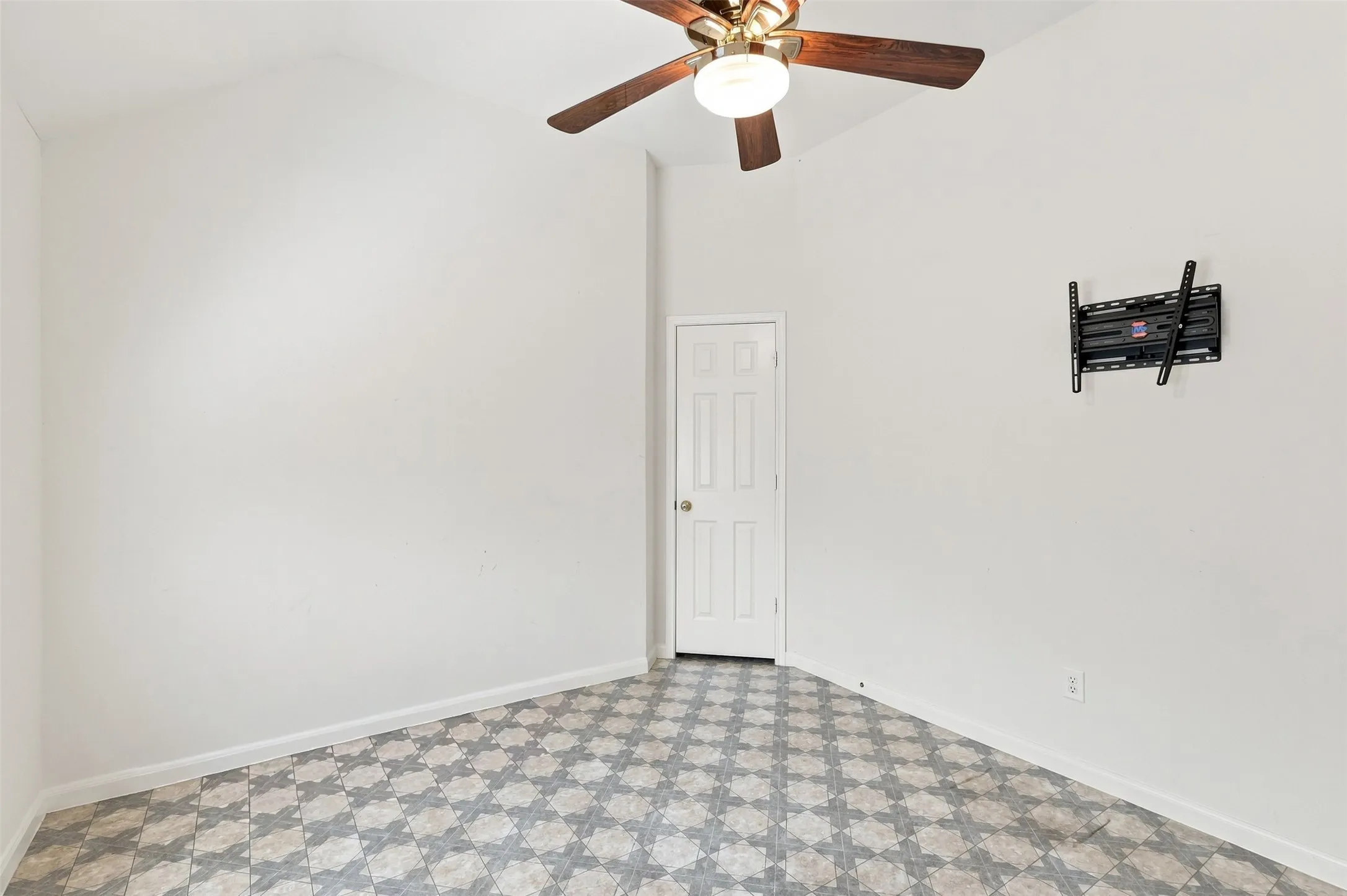 Fourth bedroom with patterned vinyl flooring and TV mount with large walk-in closet.
