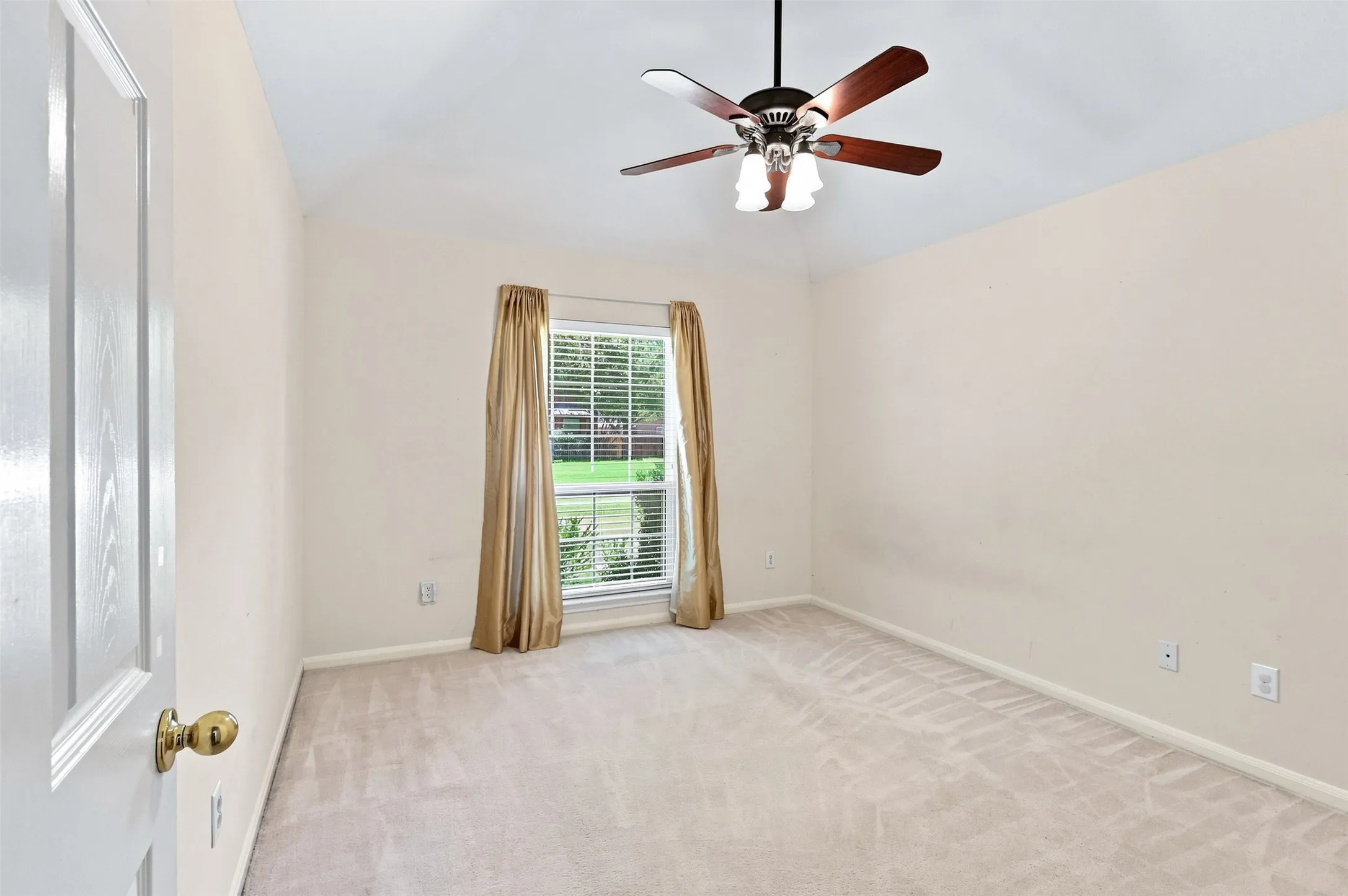Third bedroom with vaulted ceiling, window looking to front of home and neutral carpet.