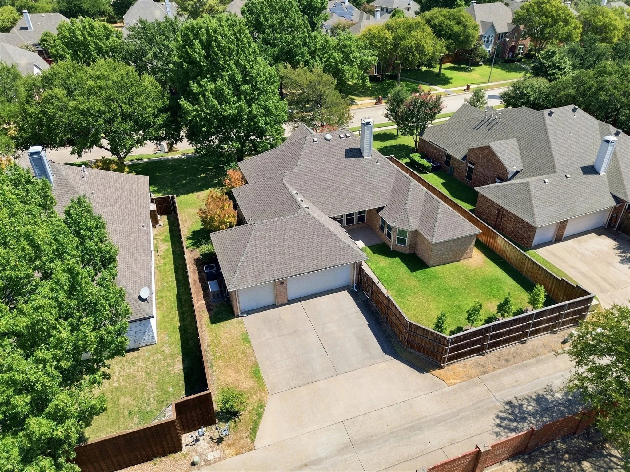 Aerial View showing brick exterior with an attached two-car garage, concrete driveway, and gabled roof, and green grass.