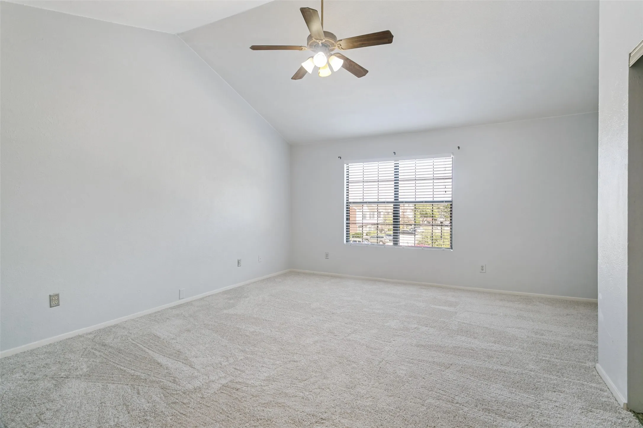 Large primary bedroom facing front of home. Plush carpet, ceiling fan and plenty of natural light