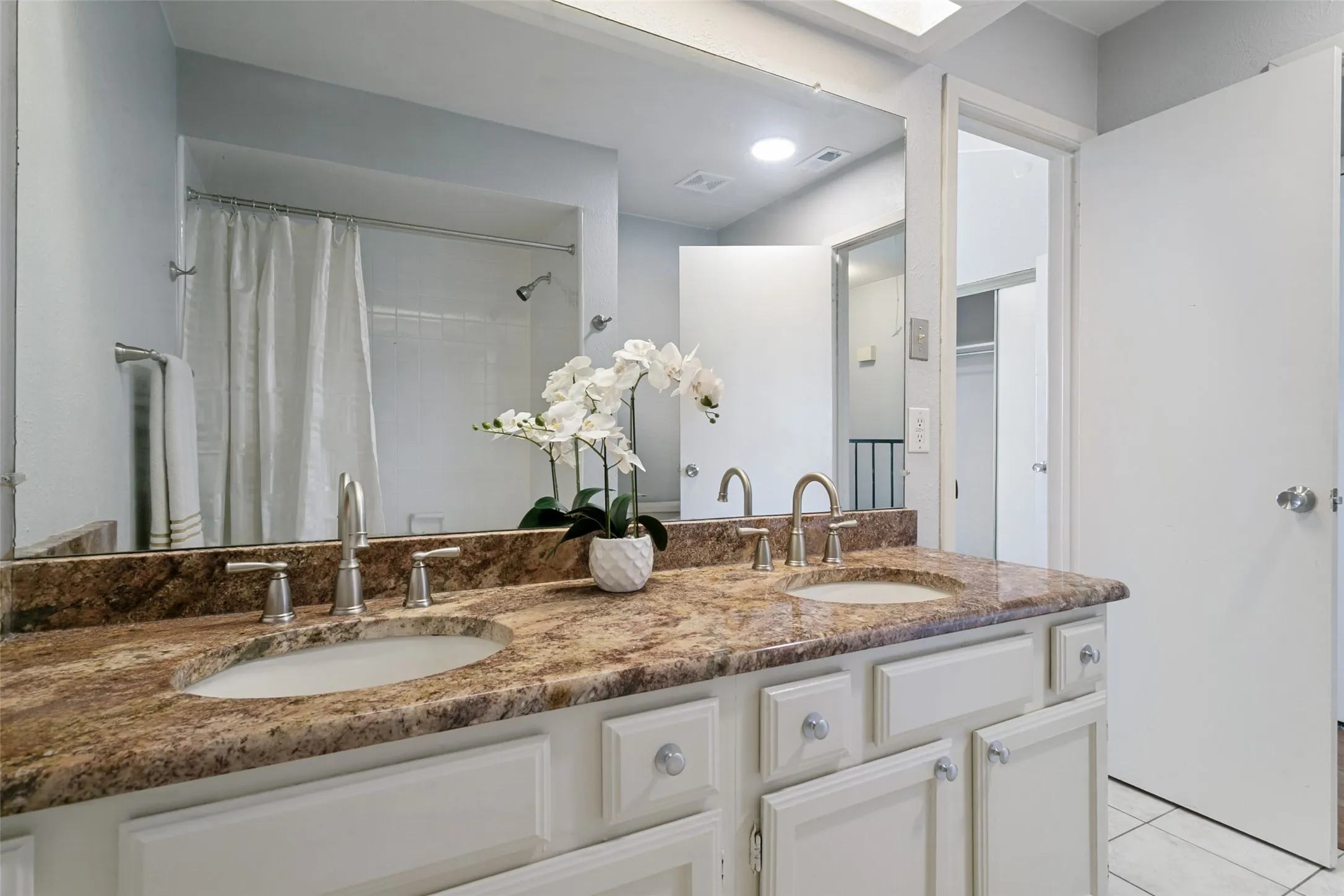Dual sinks open to primary bedroom and hallway