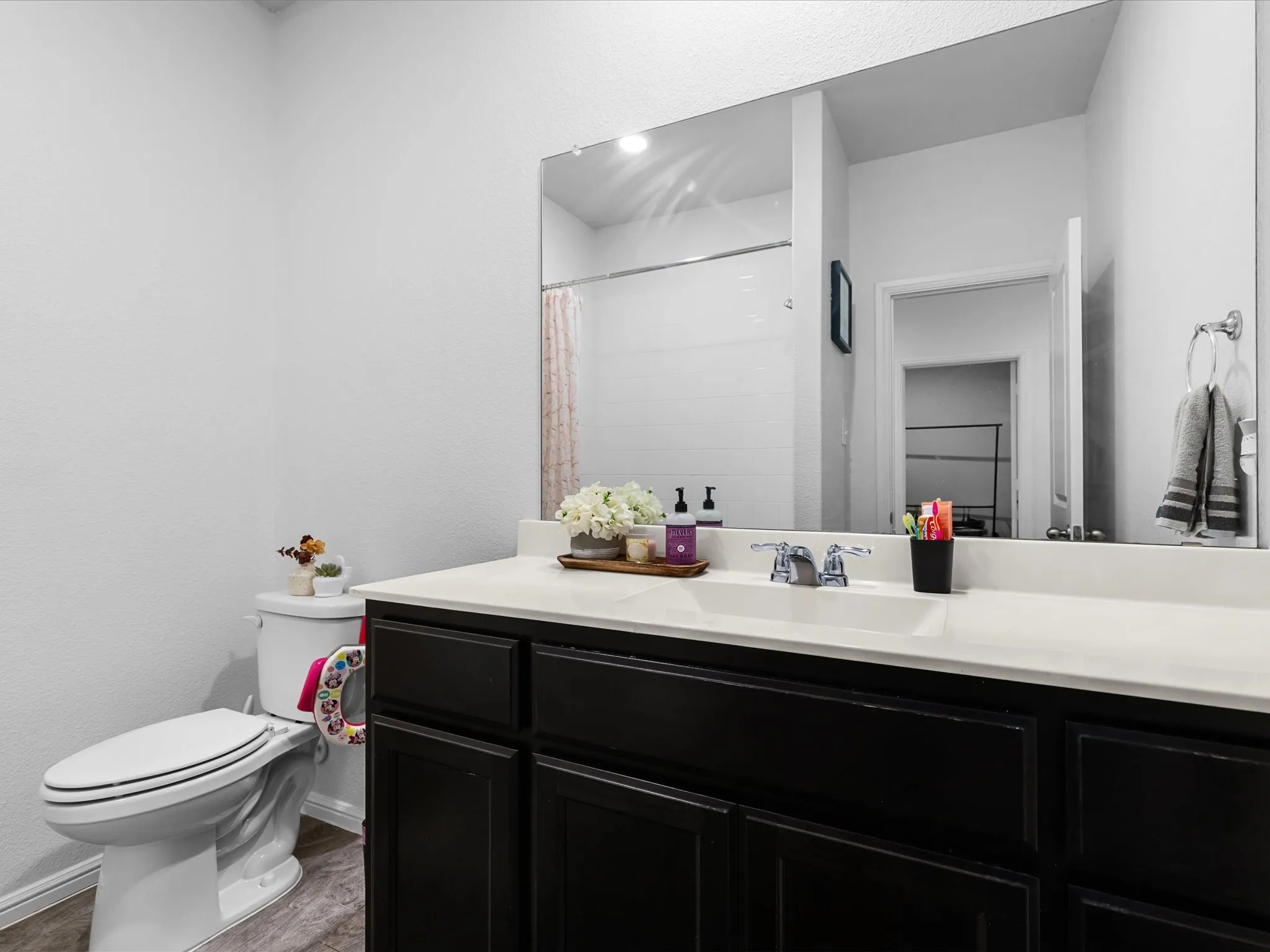 White vanity with integrated sink, black cabinetry, chrome faucet, and large wall-mounted mirror