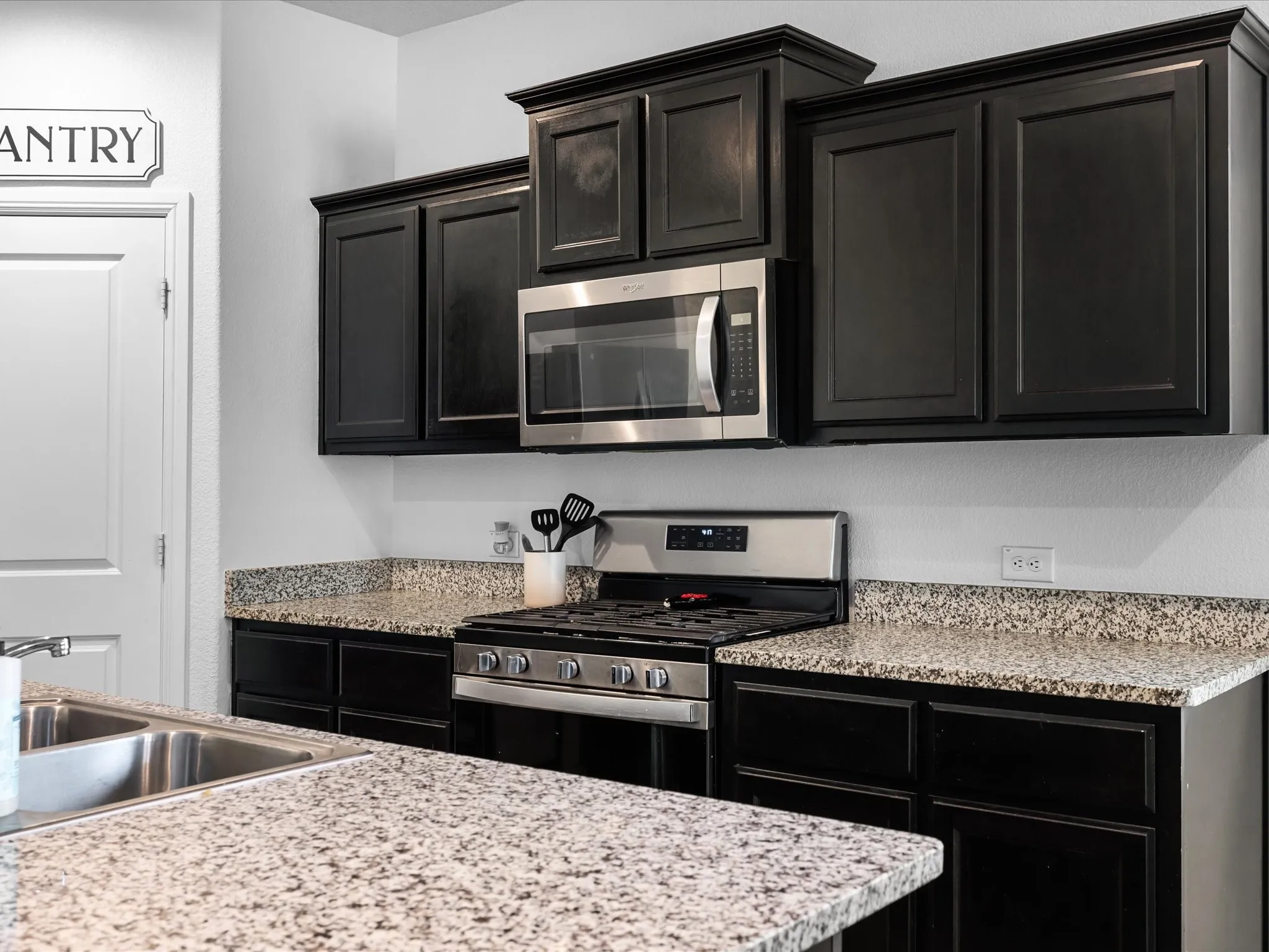 Black cabinetry, stainless steel appliances, granite-look countertops, and a double basin sink