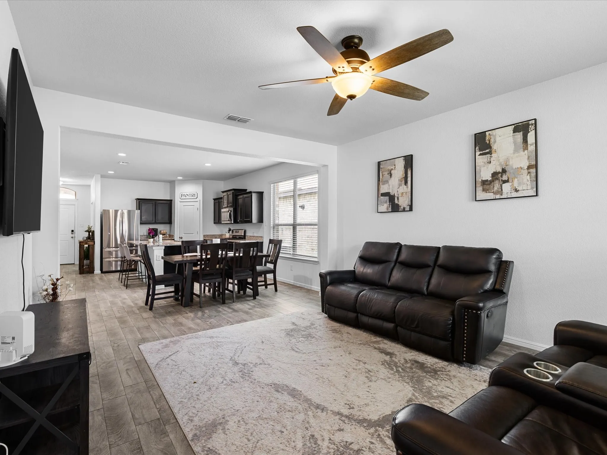 Open-concept living space featuring wood-finish flooring, recessed lighting, and a ceiling fan