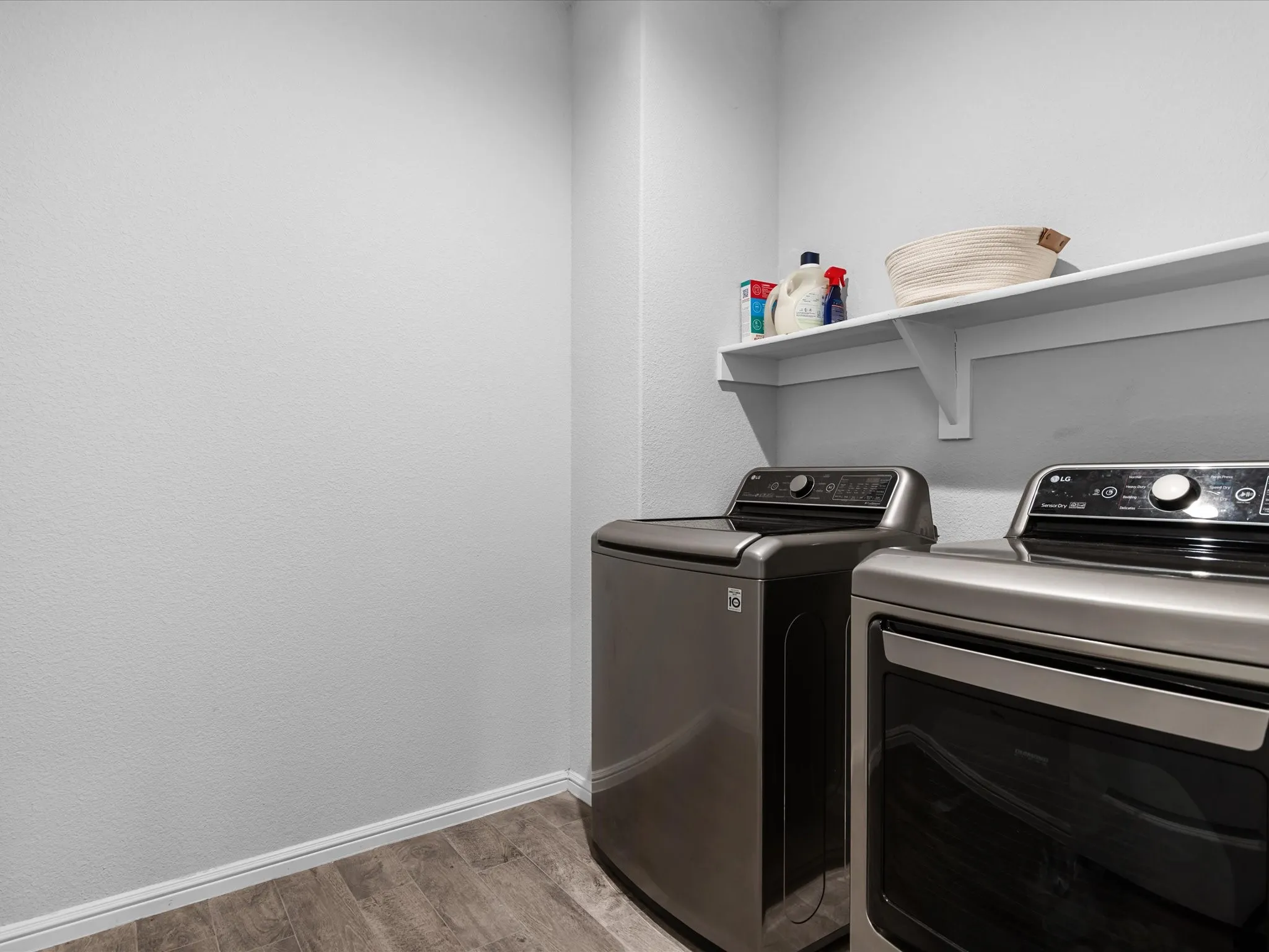 Wood-finish flooring with white baseboards, featuring a white wall shelf with bracket supports