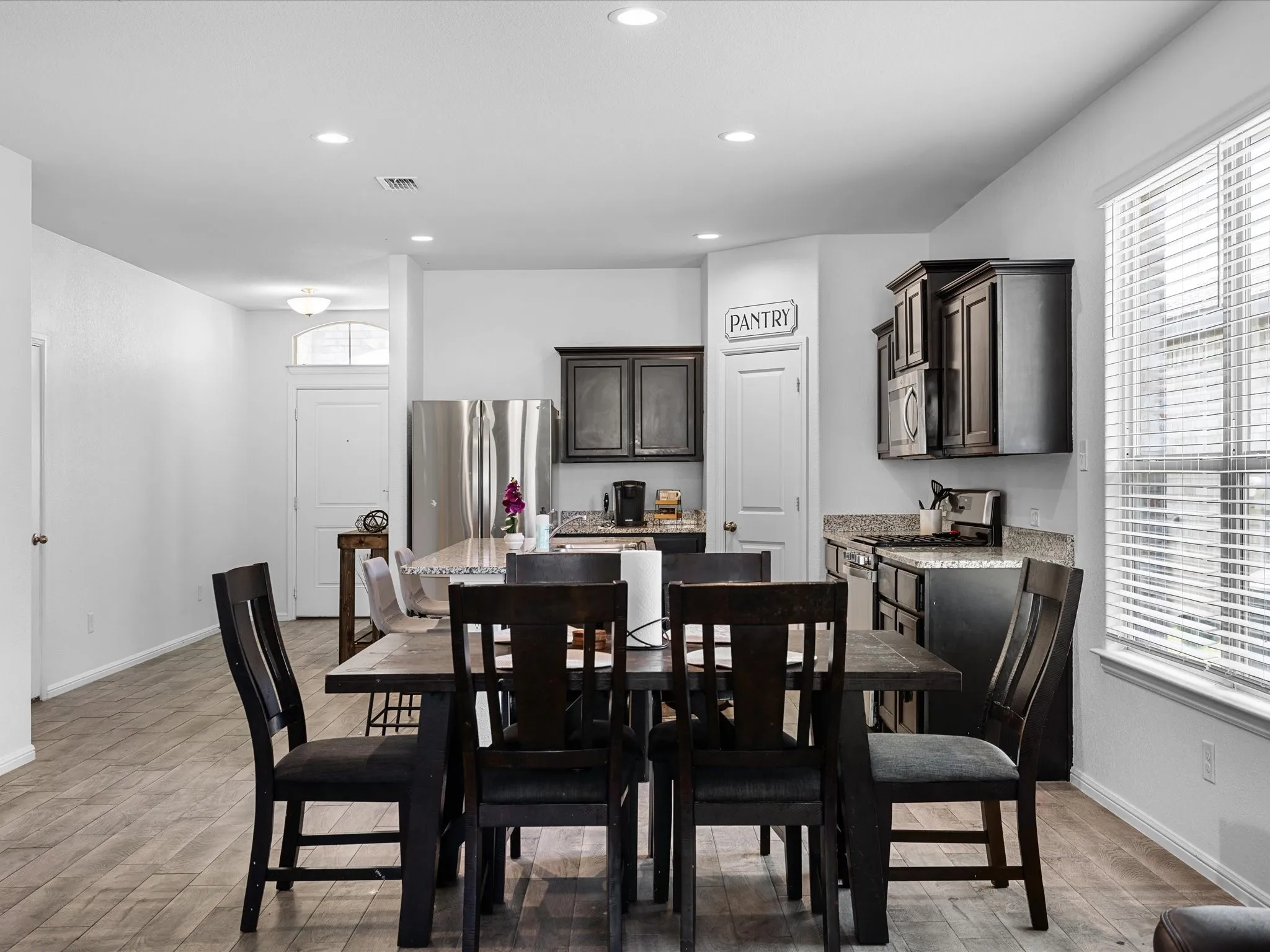 Open-concept kitchen and dining area featuring recessed lighting, wood-finish flooring, and dark cabinetry
