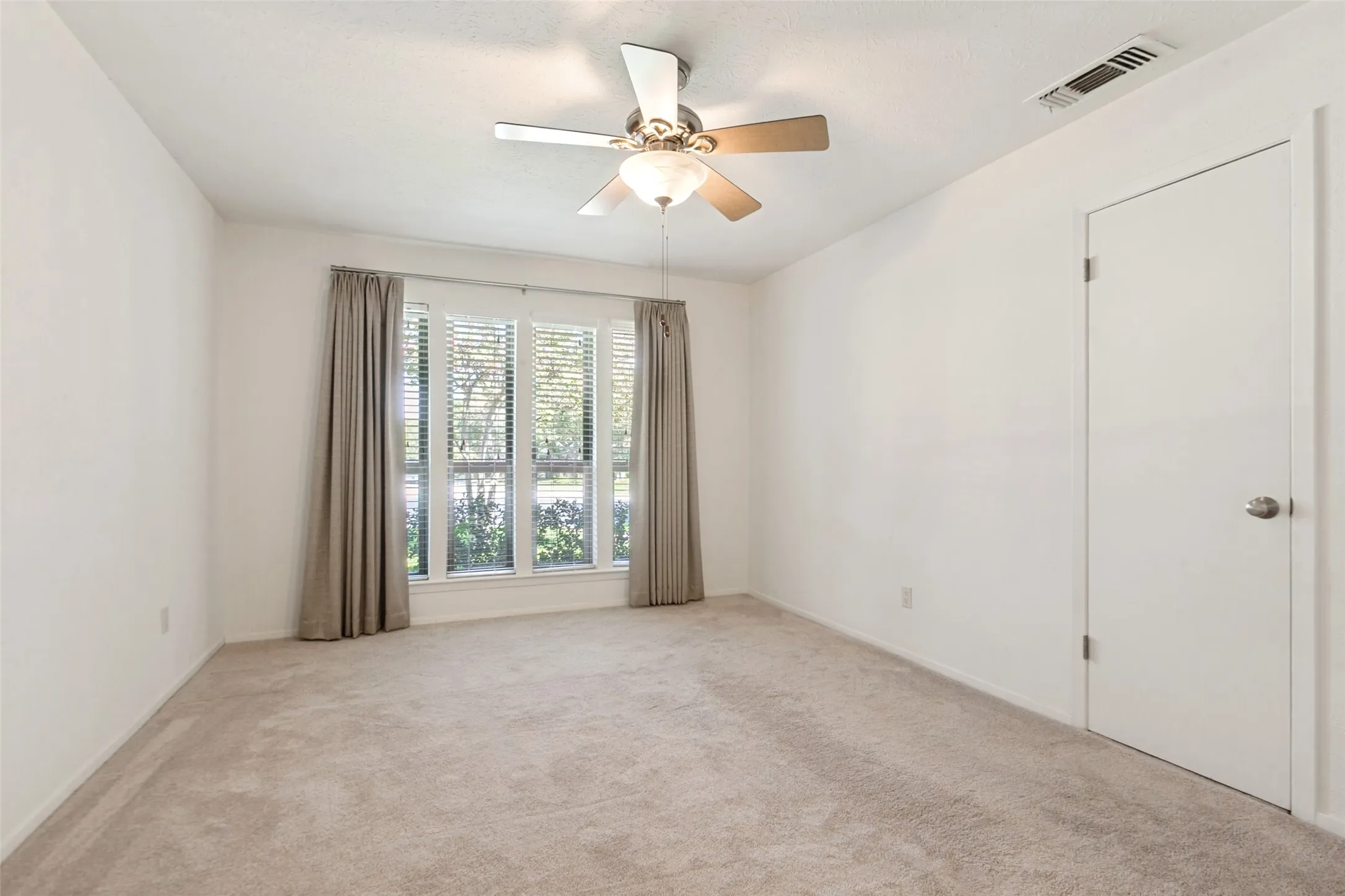 Carpeted room featuring a ceiling fan with integrated lighting, a window with blinds, and white walls