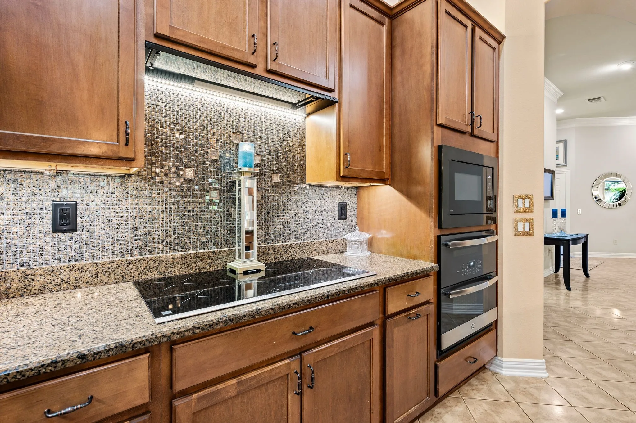 Kitchen featuring built-in appliances, a cooktop, stone countertops, and a tiled backsplash
