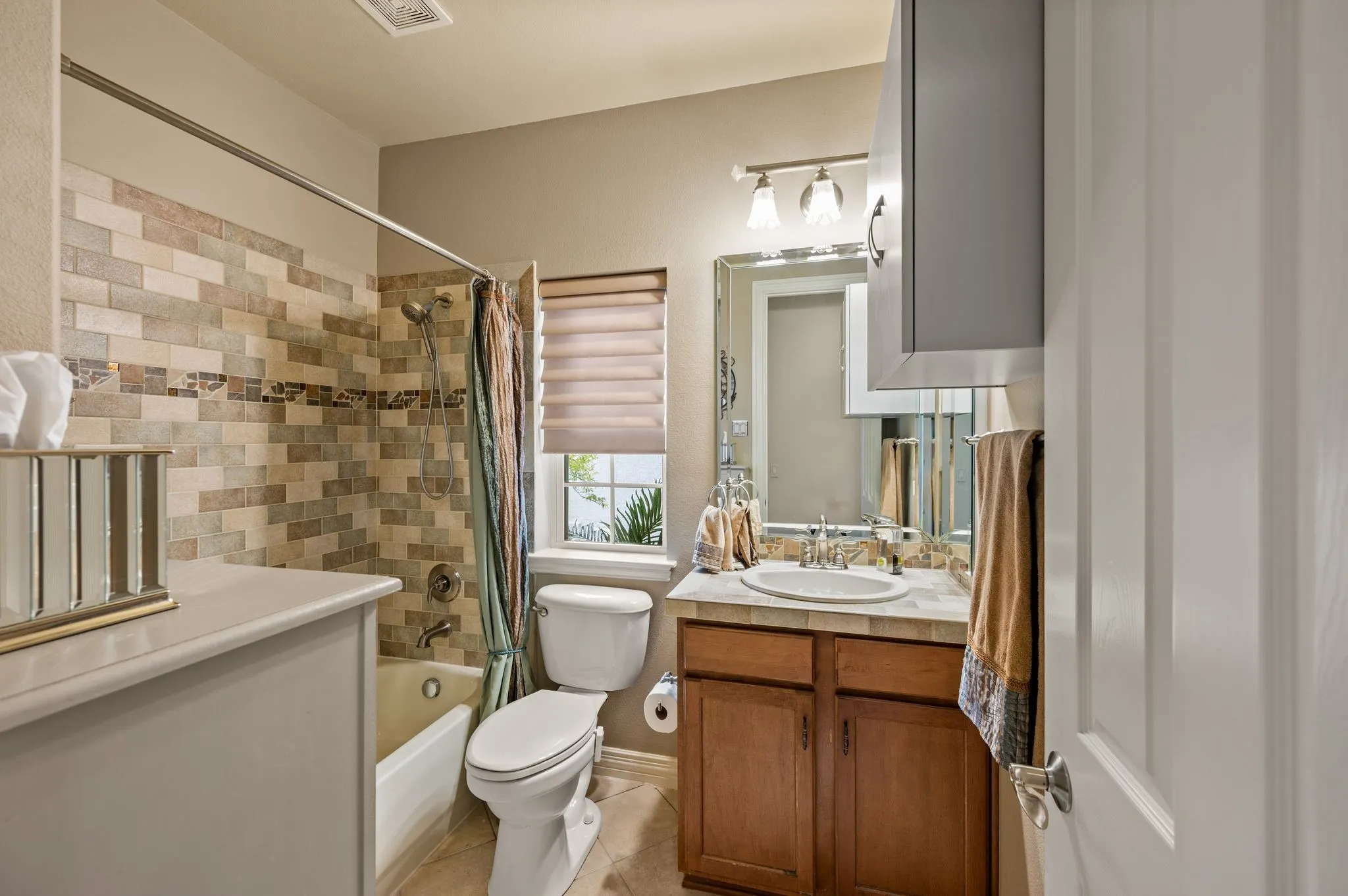 Bathroom featuring a tiled shower surround, built-in vanity with a countertop, recessed lighting, a window with blinds, and a wall-mounted medicine cabinet
