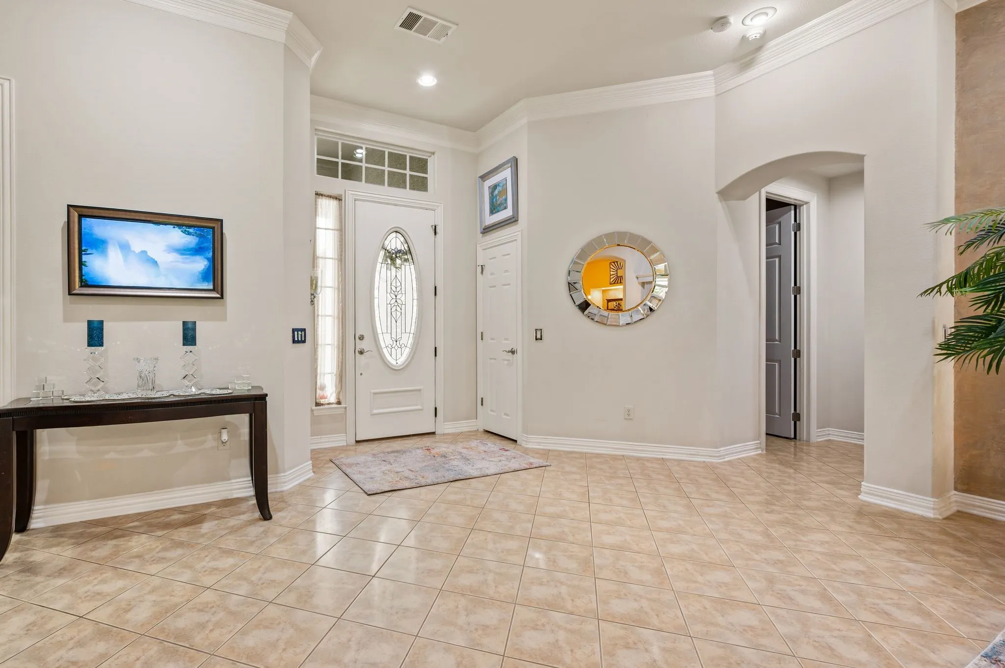 Entry foyer with tile flooring, crown molding, and an arched doorway