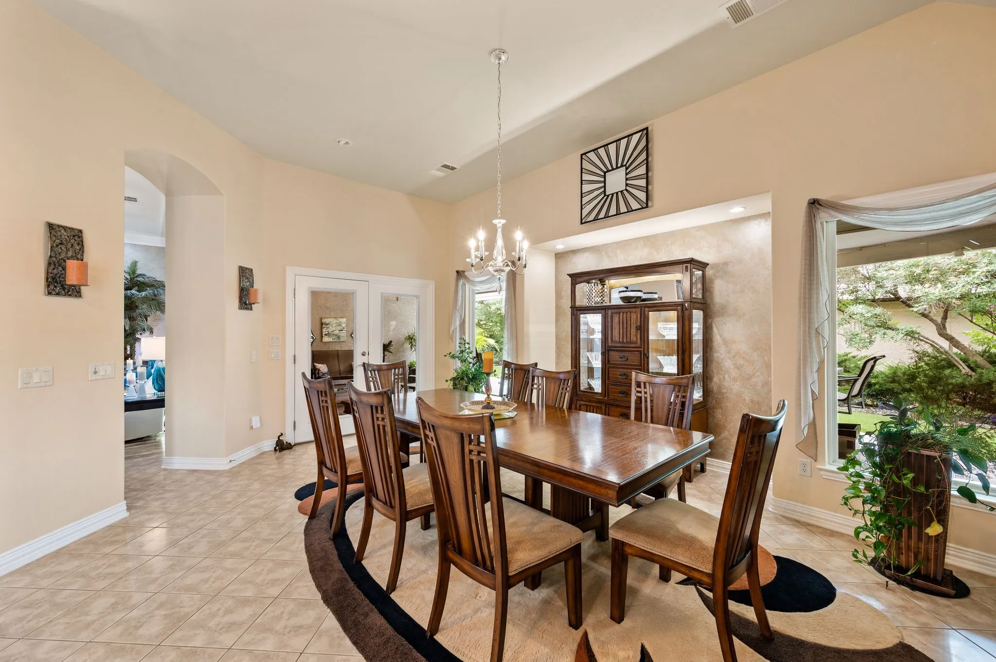 Formal dining area featuring neutral tile flooring, arched entryways, and a large picture window
