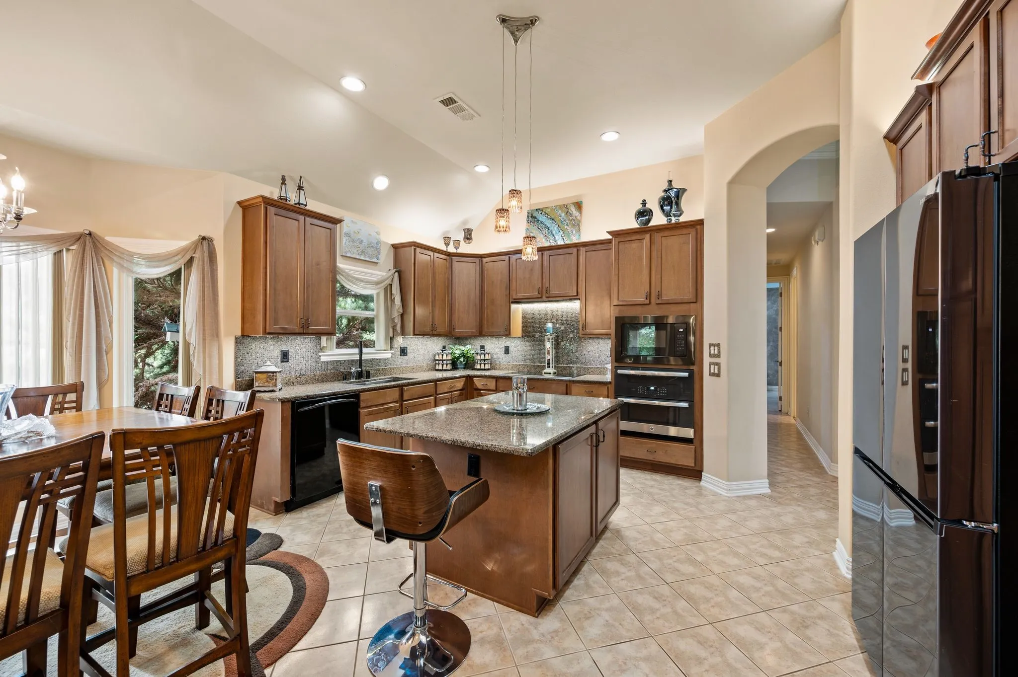 Kitchen featuring a central island with a granite countertop, wood-finish cabinetry, tile flooring, and stainless steel appliances