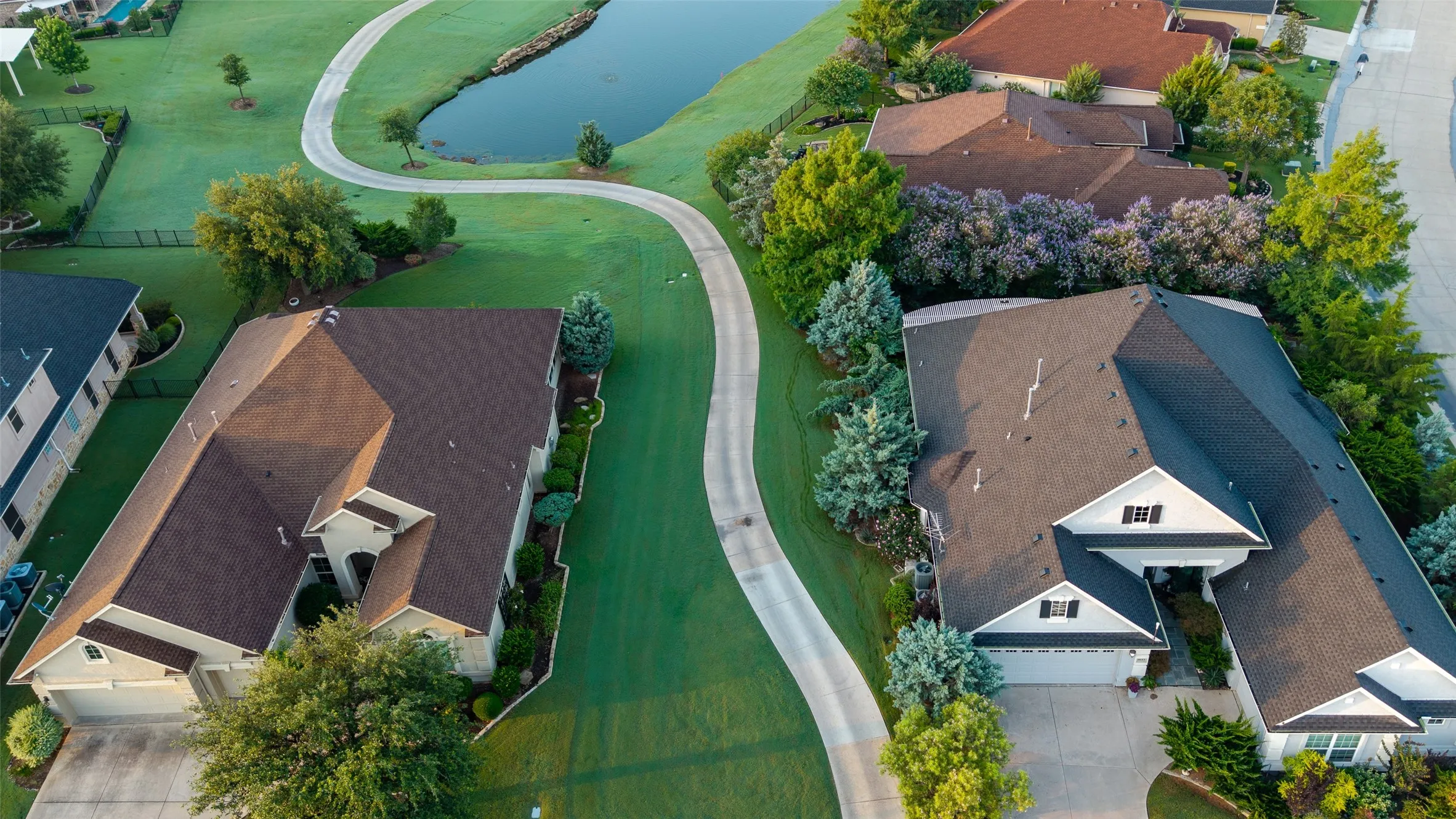 Manicured lawns with mature trees, established landscaping, and paved driveways