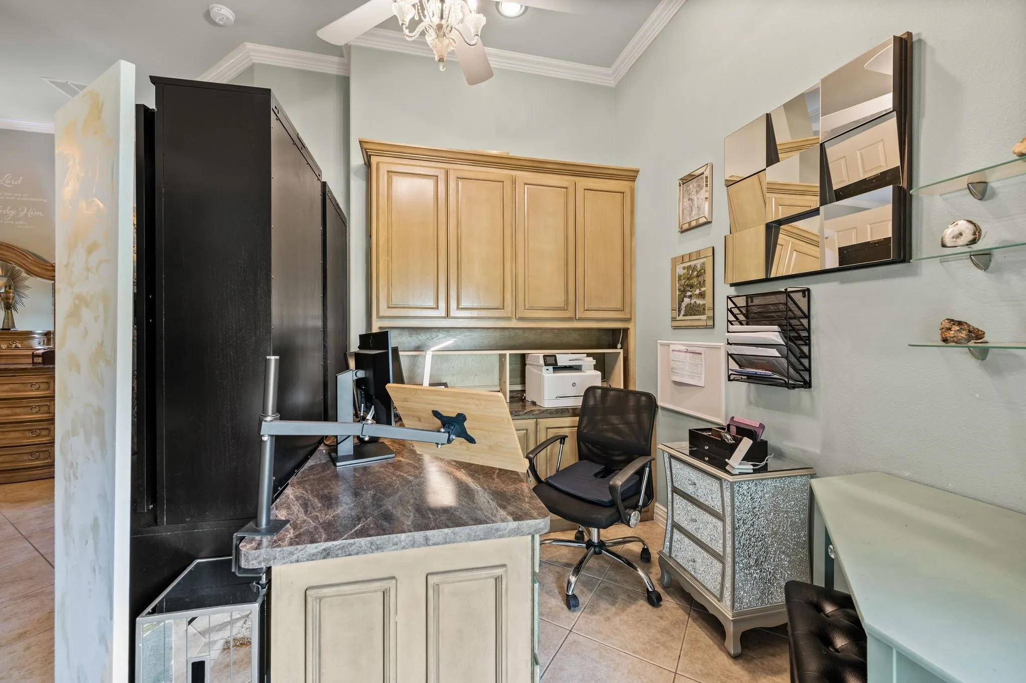 Built-in cabinetry with wood-finish doors, durable countertop surface, tiled flooring, crown molding, and a ceiling fan with integrated lighting