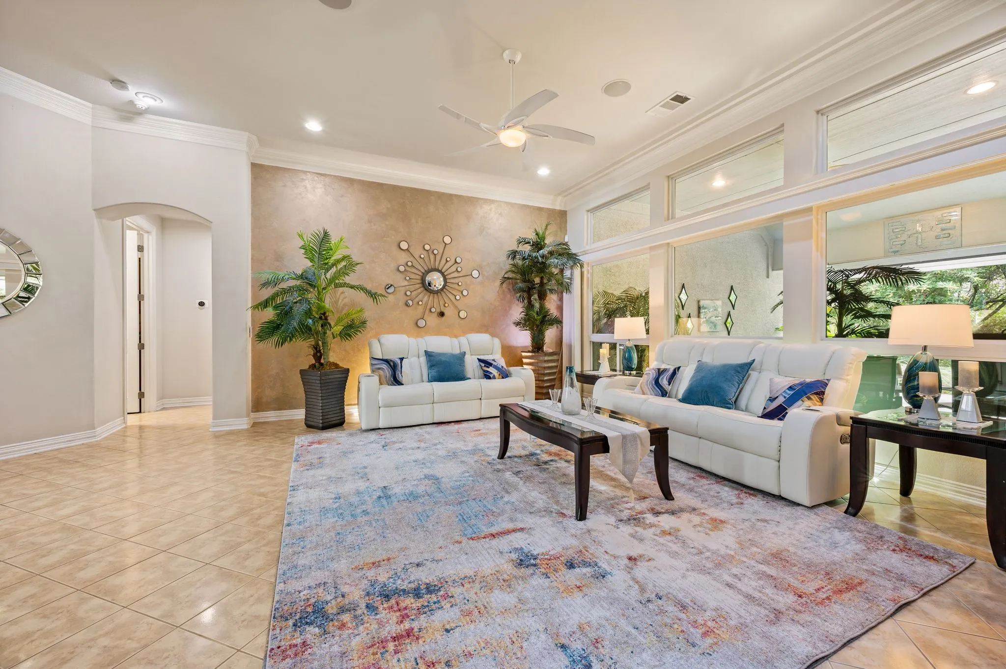 Large format tile flooring, crown molding, arched entry, tall windows, and recessed lighting