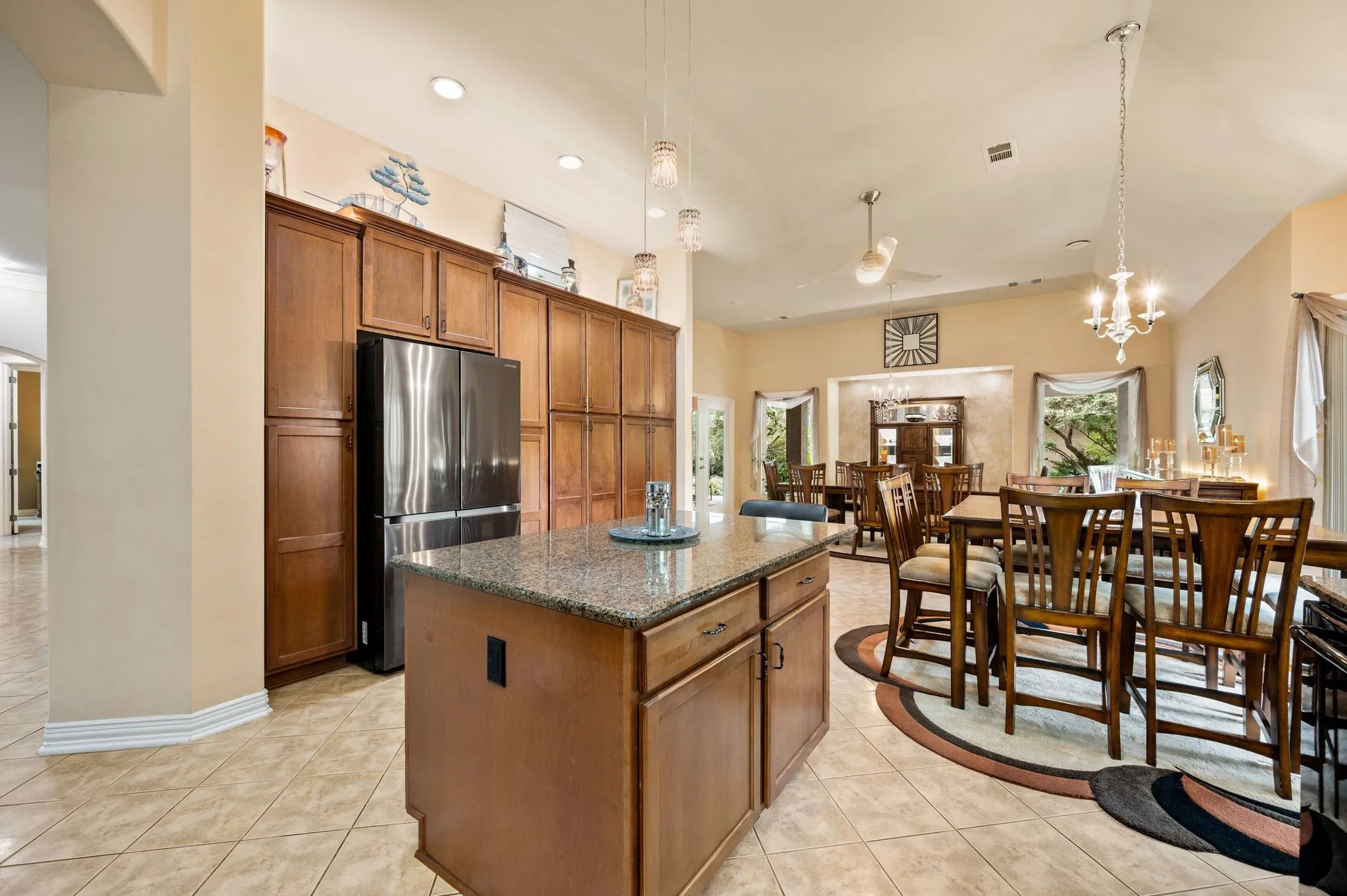 Kitchen island with granite countertop, recessed lighting, tile flooring, and dark wood cabinetry