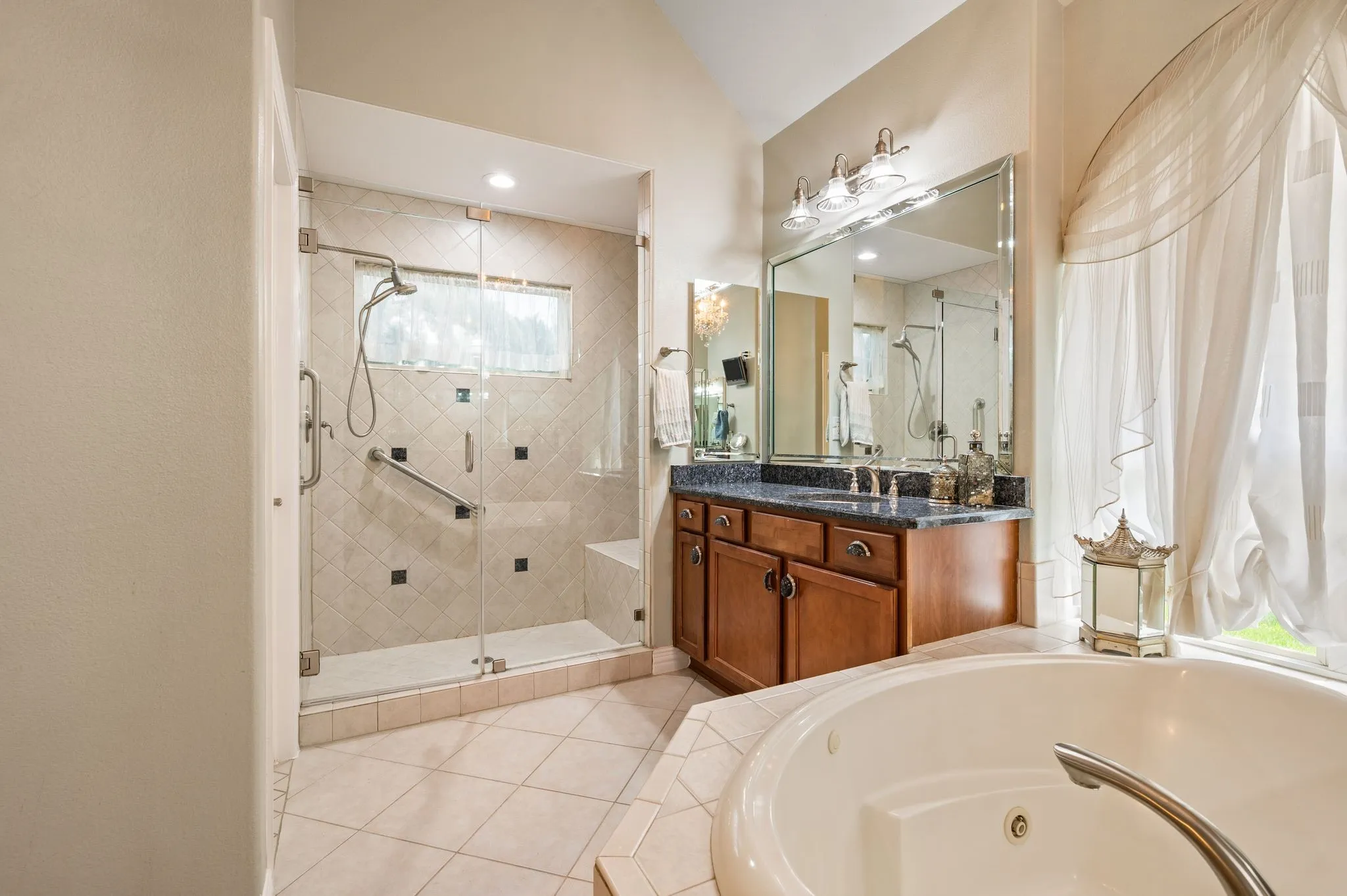 Glass-enclosed shower with tiled walls and a built-in bench, featuring a corner soaking tub