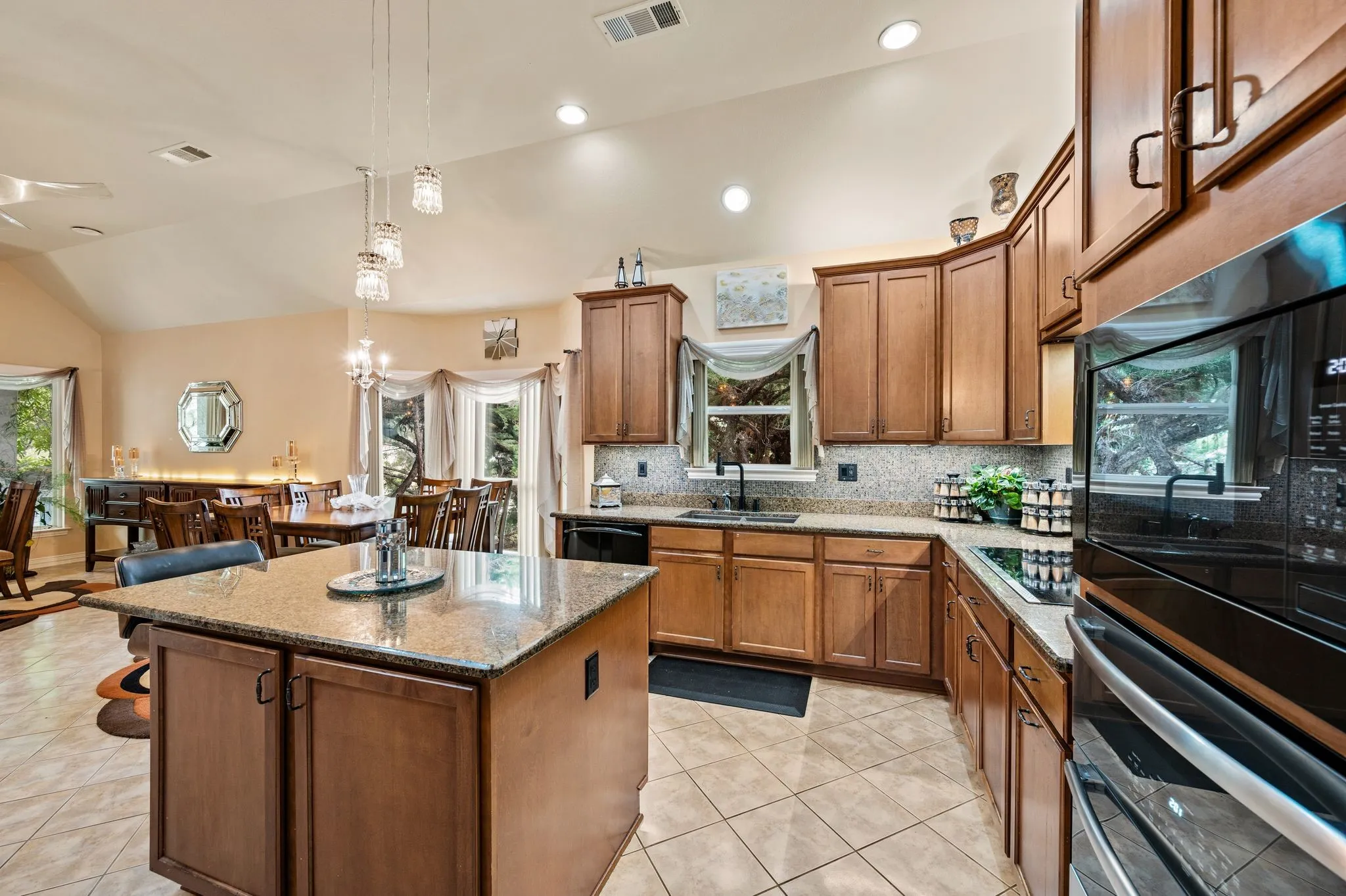 Kitchen featuring a central island with a granite countertop, wood cabinetry, tile flooring, and a built-in oven