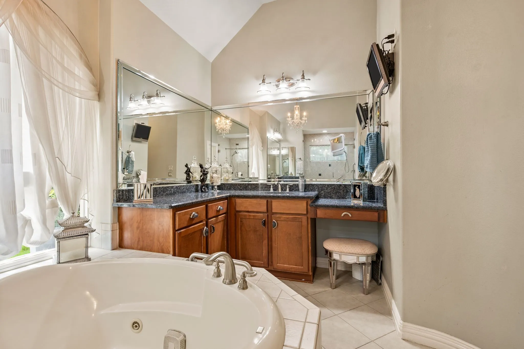 White soaking tub with brushed nickel fixtures, tile surround, and a large window