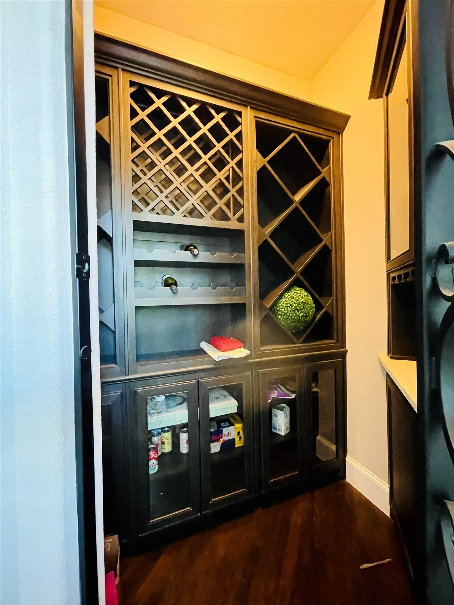 Built-in custom cabinetry with glass-front doors, diamond-patterned wine storage, and wood-finish flooring