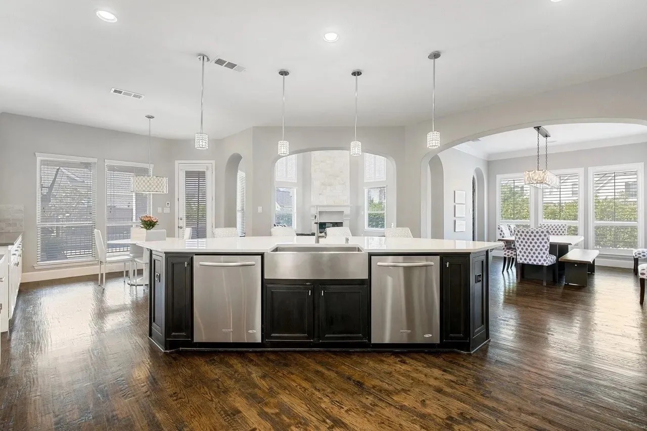 Kitchen island with a farmhouse sink, stainless steel appliances, and pendant lighting