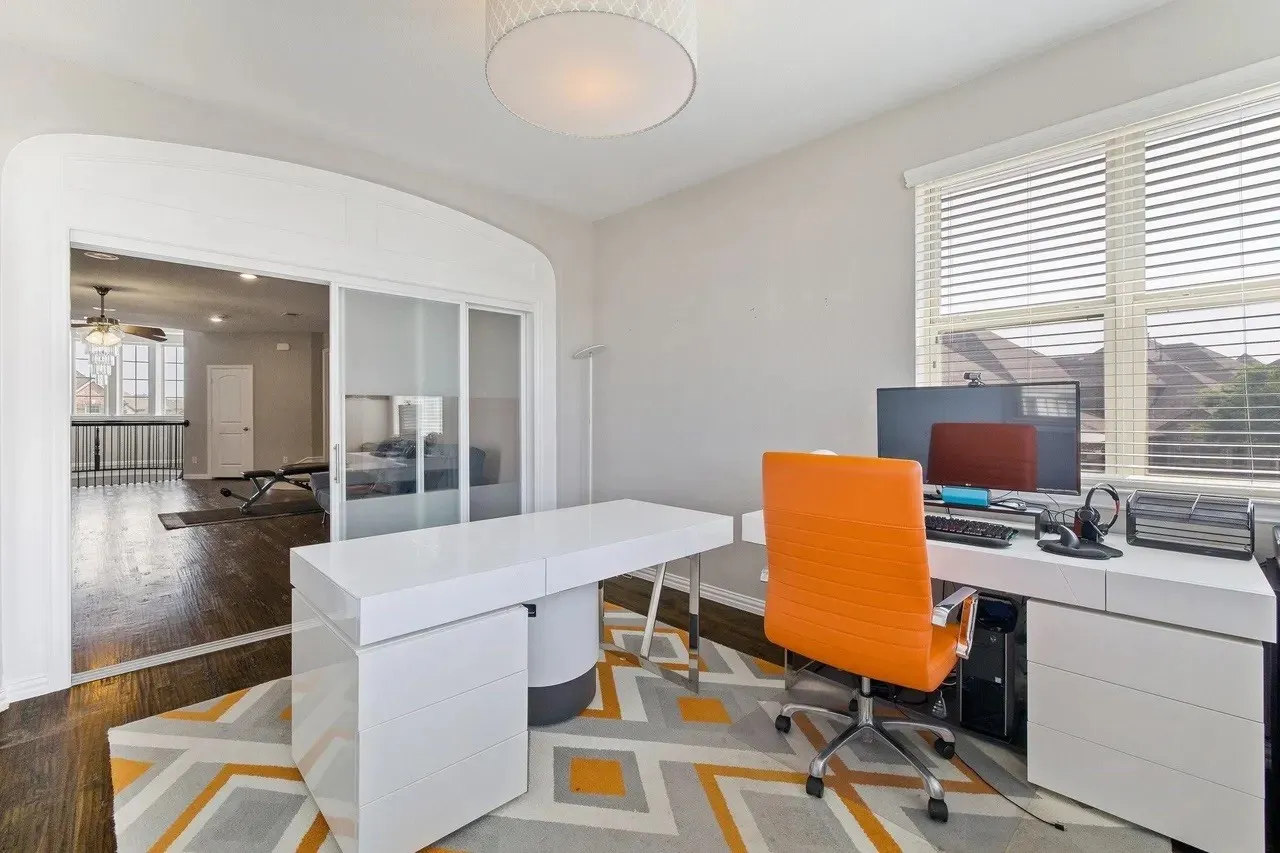 Archway opening, wood-finish flooring, sliding opaque glass panels, white window blinds, and a drum pendant light fixture