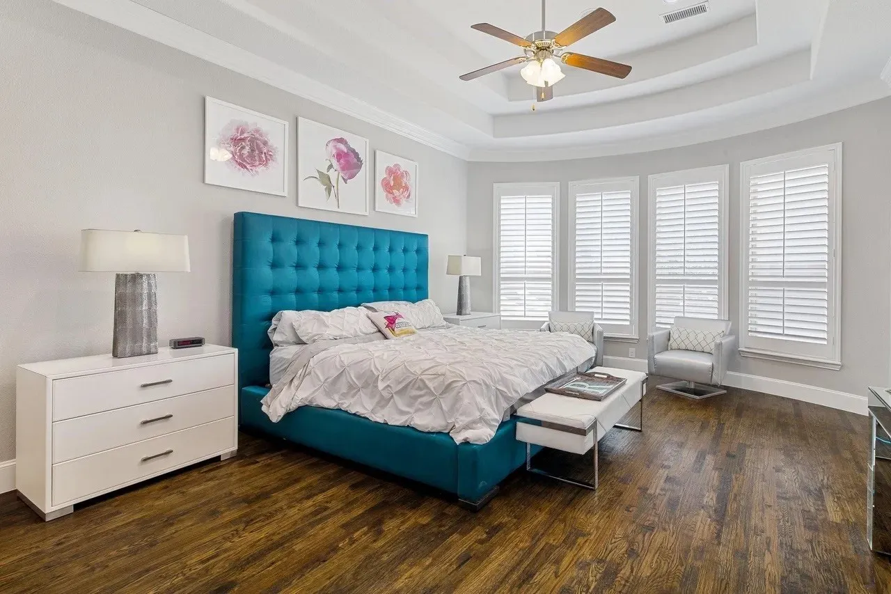 Hardwood-style flooring, tray ceiling with a ceiling fan, white plantation shutters, and recessed lighting