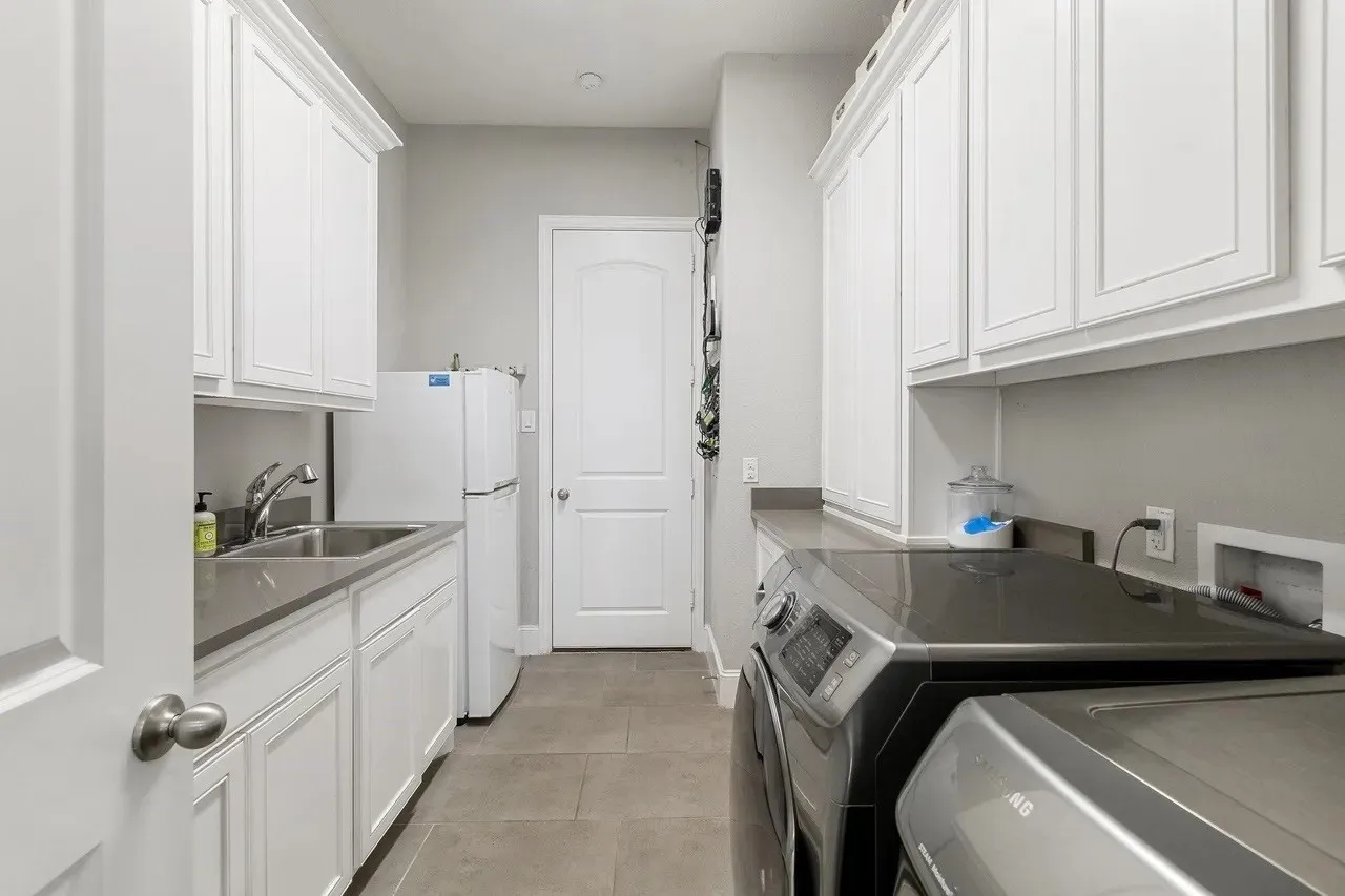Built-in cabinetry, stainless steel sink, countertop workspace, and tile flooring