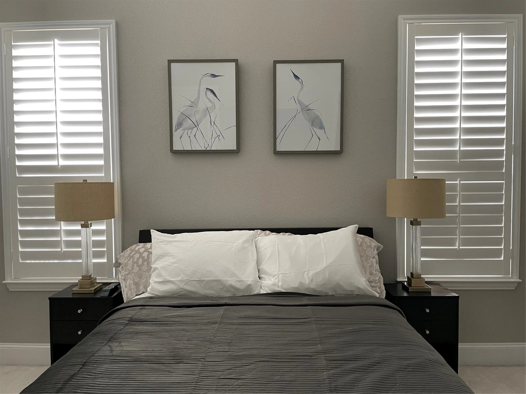 White plantation shutters frame windows, complementing the neutral wall tones